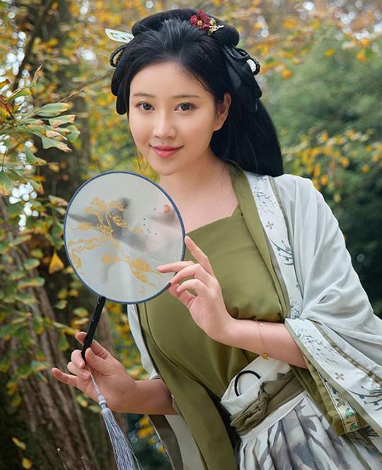 当秋风吹过,树叶如彩蝶般飘落,一把古装小圆扇轻轻摇曳在手中.