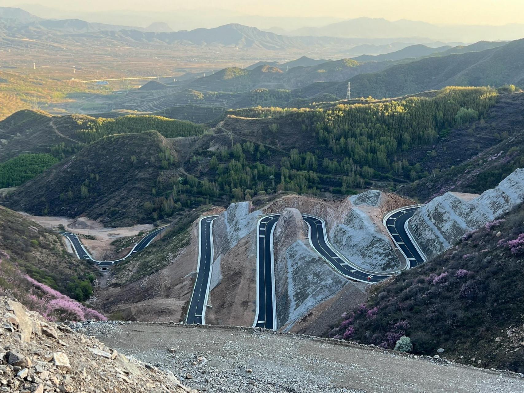 它是一条盘山公路,几十道拐公路坡陡,蜿蜓起伏宛如一条巨龙萦绕着山岭