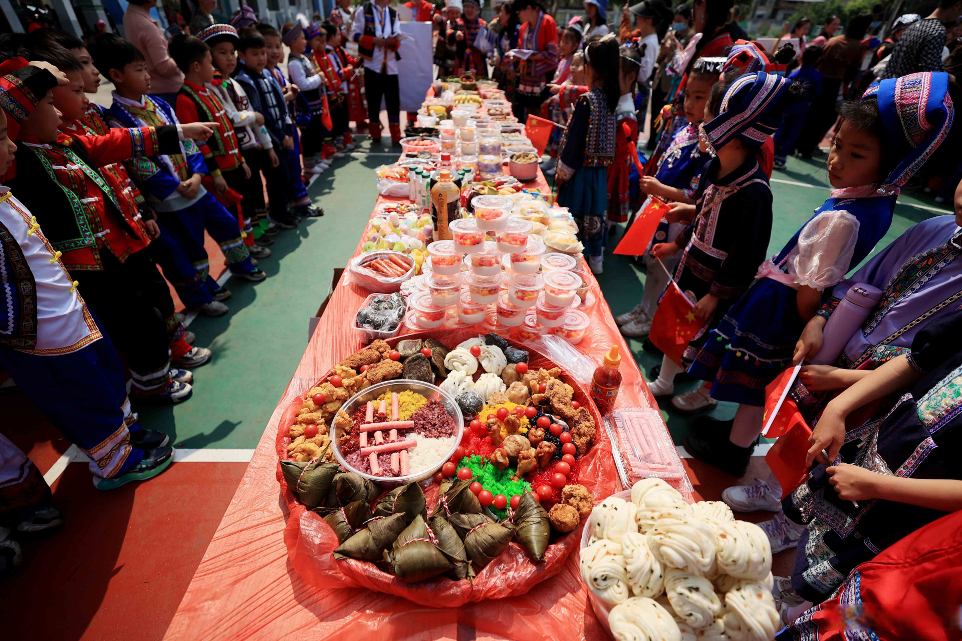 学生们在广西柳州市融安县实验小学校园品尝"百家宴"