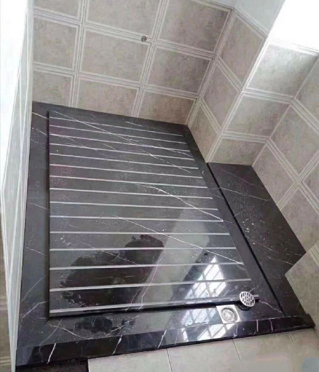 用机器进行拉槽加工,将其铺贴在淋浴房的中心,周围会有一圈导流排水槽