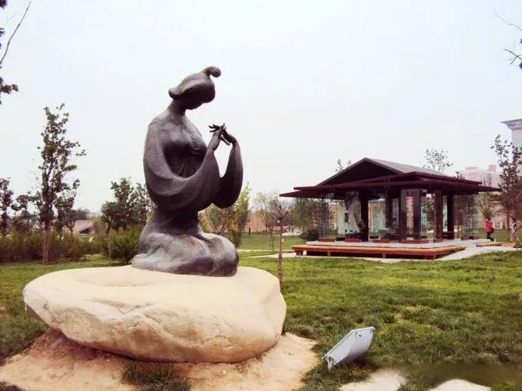 梅妃亭前,掩映在梅花树下的梅妃铜塑像低头吹笛,她席地跪坐,臀部放