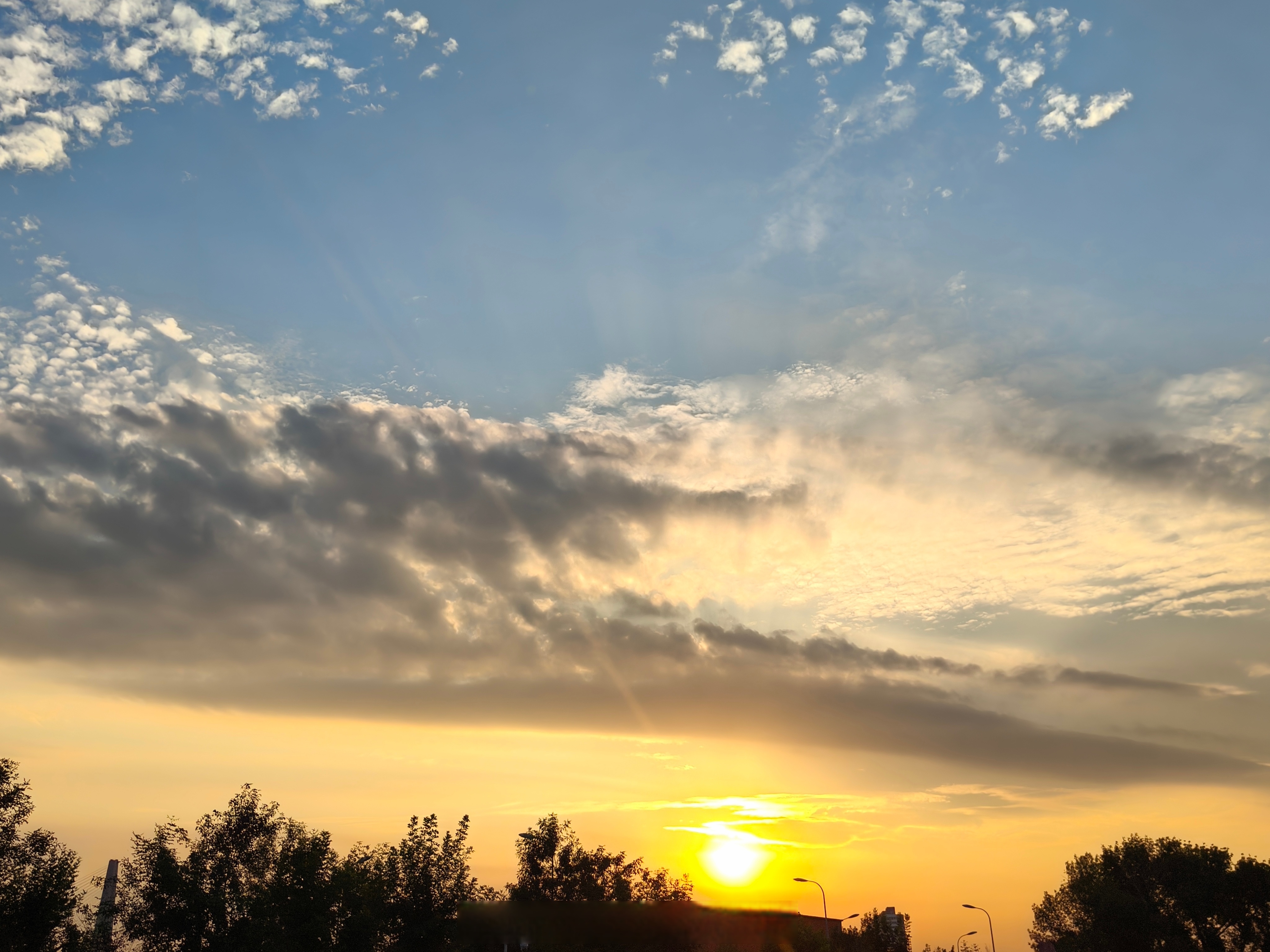 厚重的云层在天际堆叠,如同一座棉花山被夕阳点燃,只见几道金色光线从