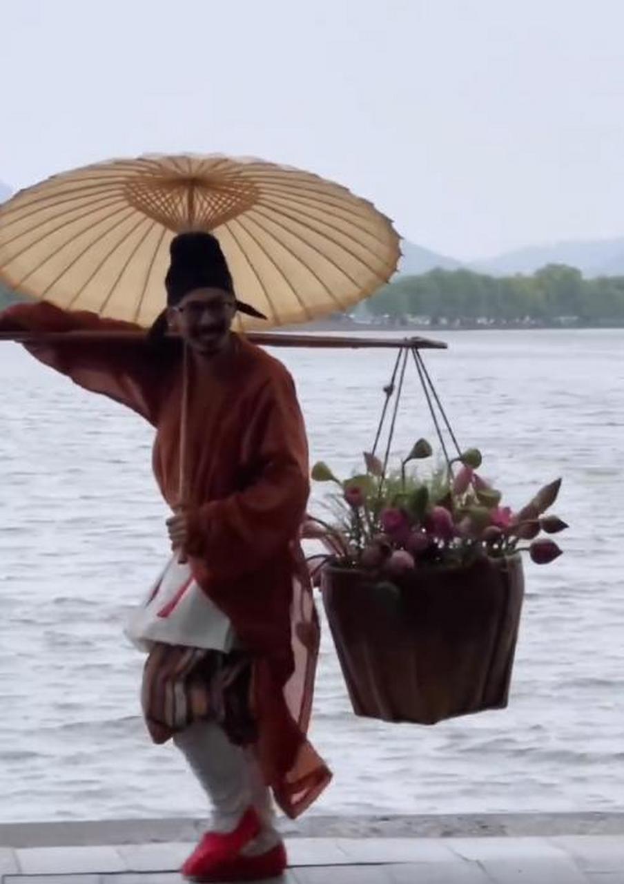 西湖偶遇卖花郎送荷花】近日,杭州西湖边,有网友偶遇古风爱好者装扮成