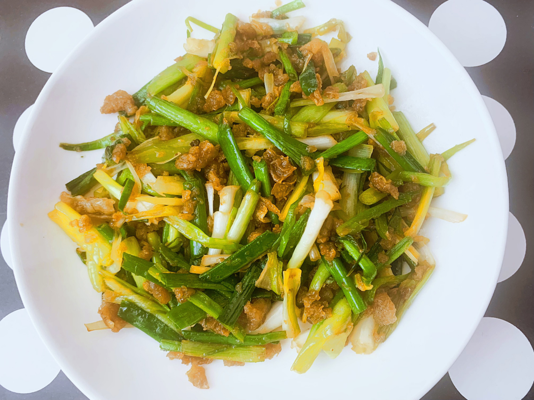 第二部,将猪油渣放入锅中,炒到猪油渣会冒一些小泡,加入韭菜或蒜苗