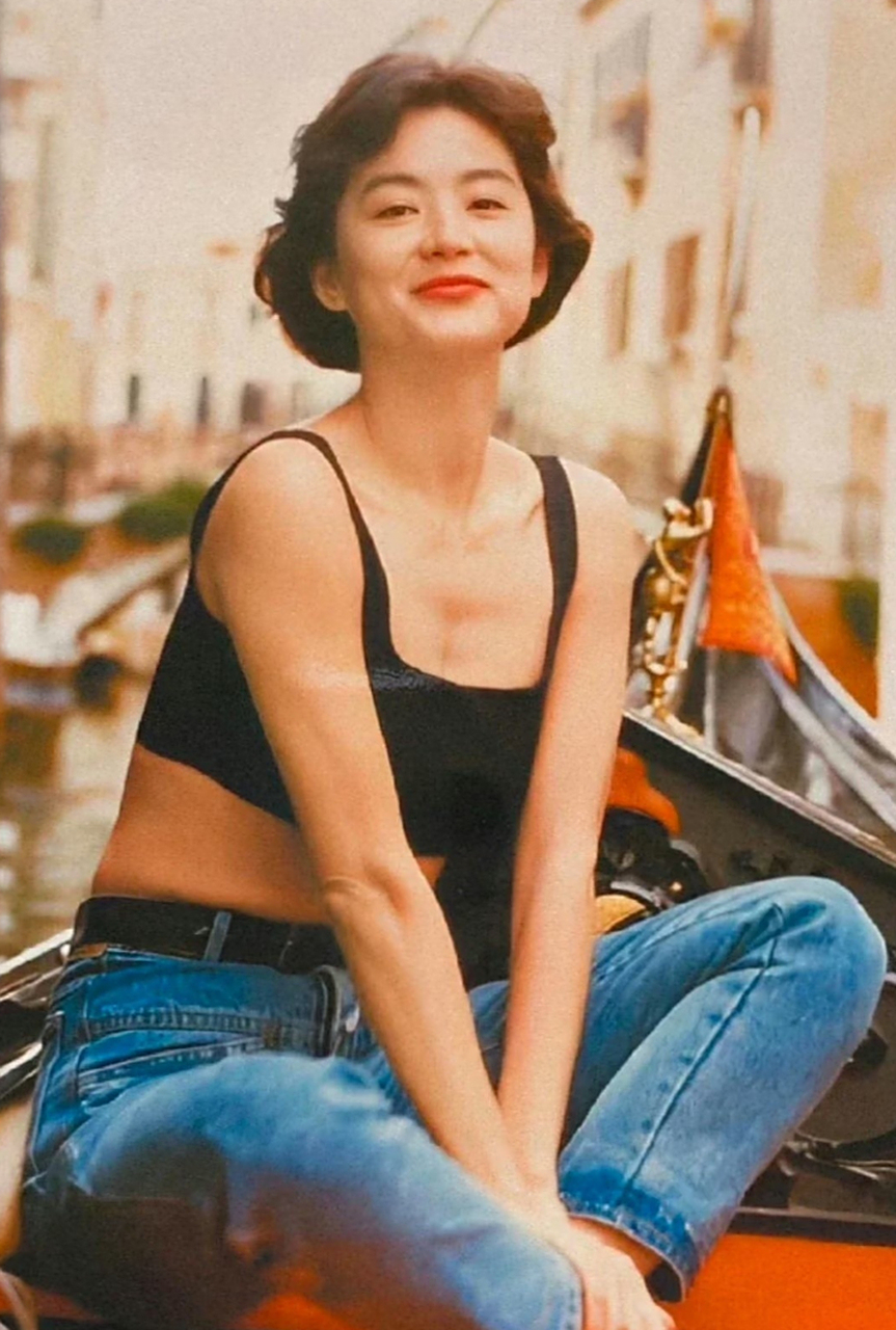 981989年的林青霞,穿着黑色短背心和蓝色牛仔裤,搭配赫本头发型