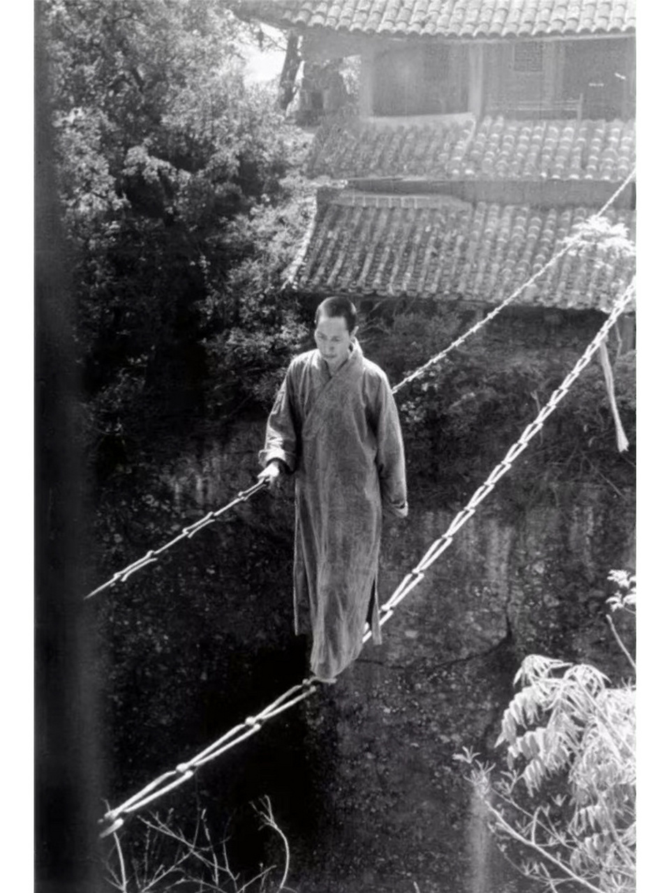 1930年代,四川 江油窦团山上寺庙,一位僧侣以简易的铁索为桥,僧侣神色