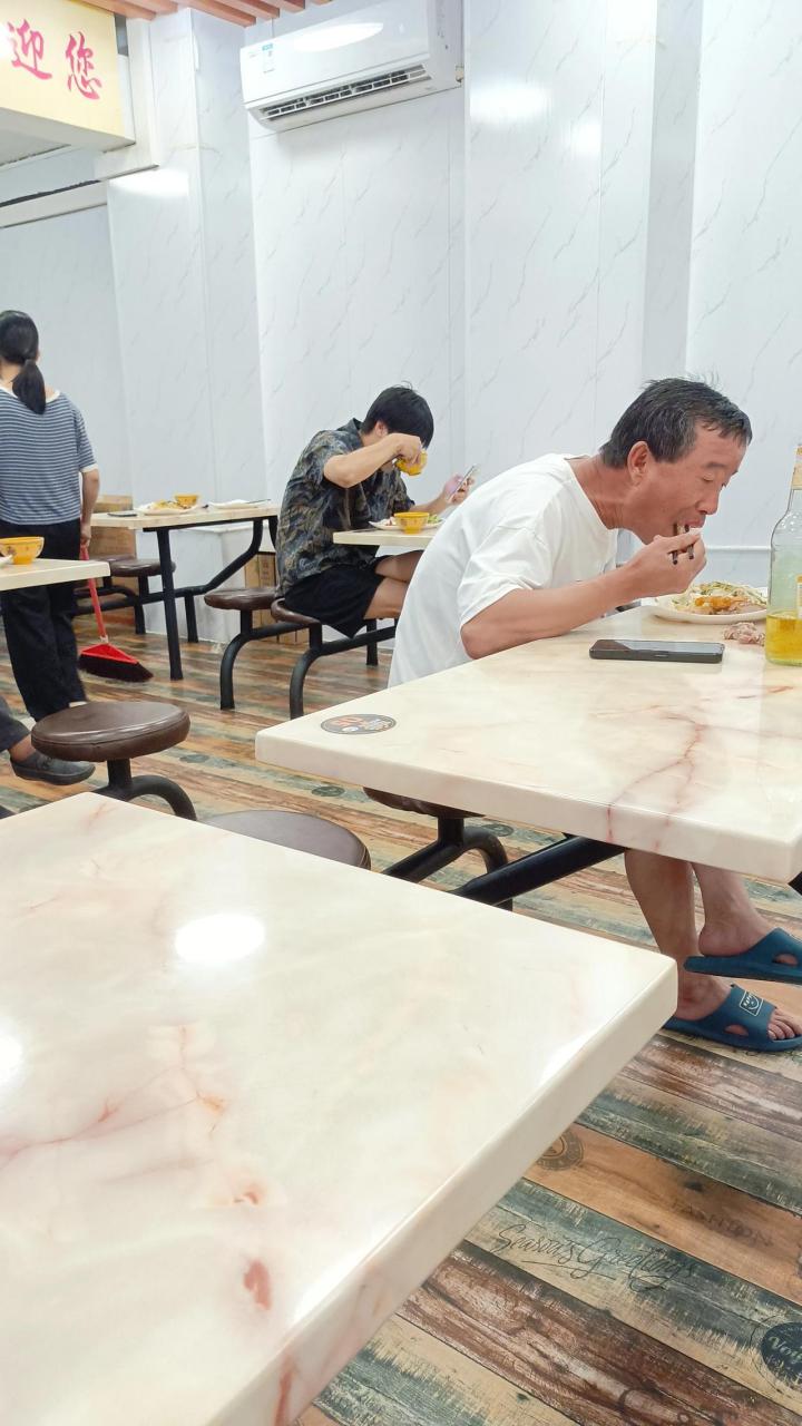 一位大叔在快餐店吃饭,也想像别人那样边吃边看视频,可惜他手机里没有