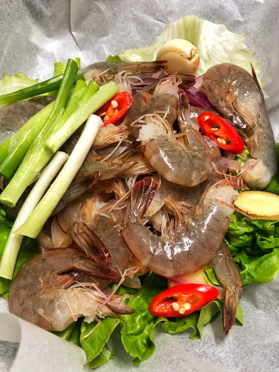 懒人菜系列 【纸包虾】硅油纸铺上生菜和爆香后的洋葱,蒜瓣;控干水分