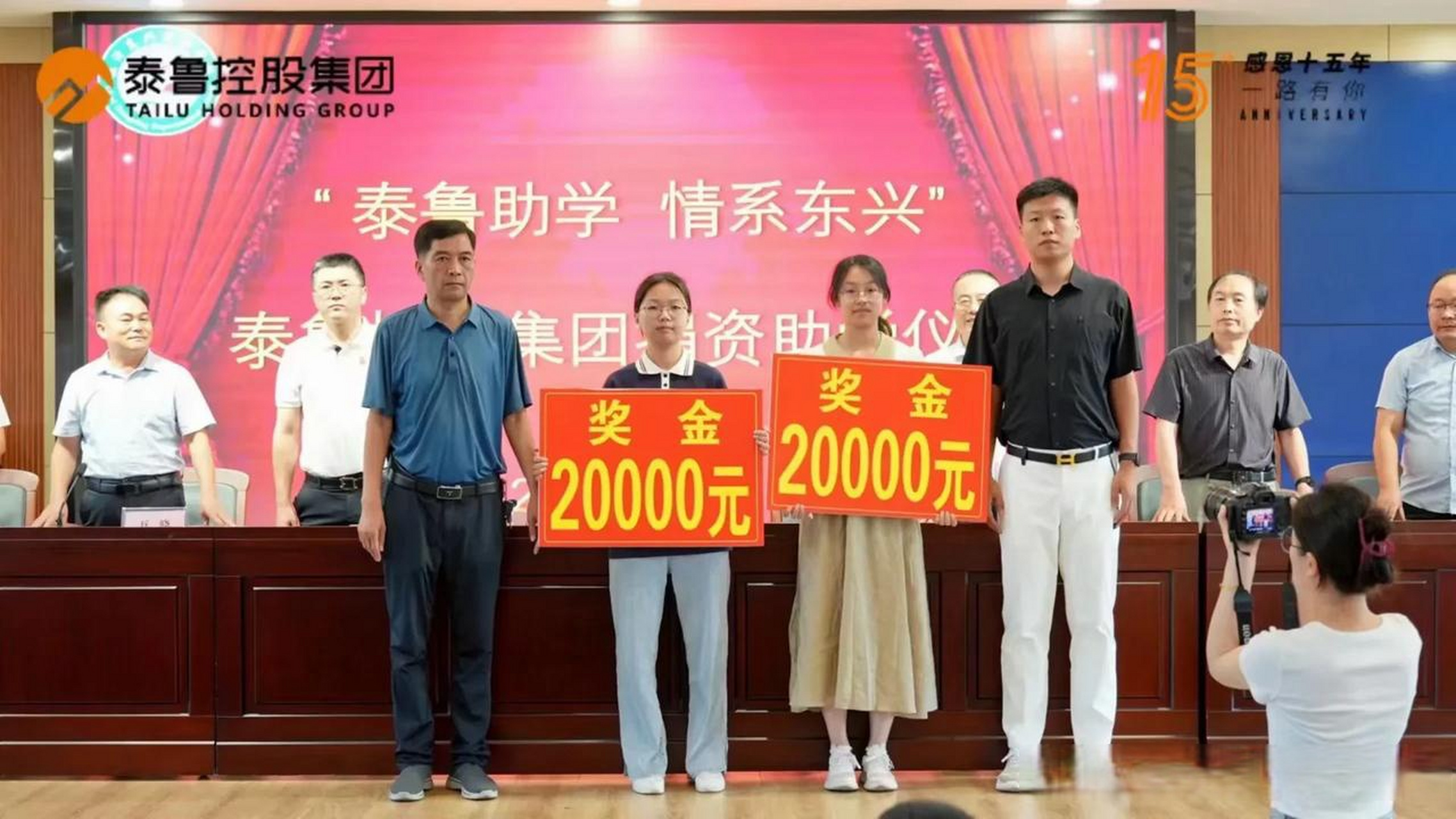 台上优秀学子们手握奖金牌,河东区东兴实验学校和泰鲁集团为他们颁奖