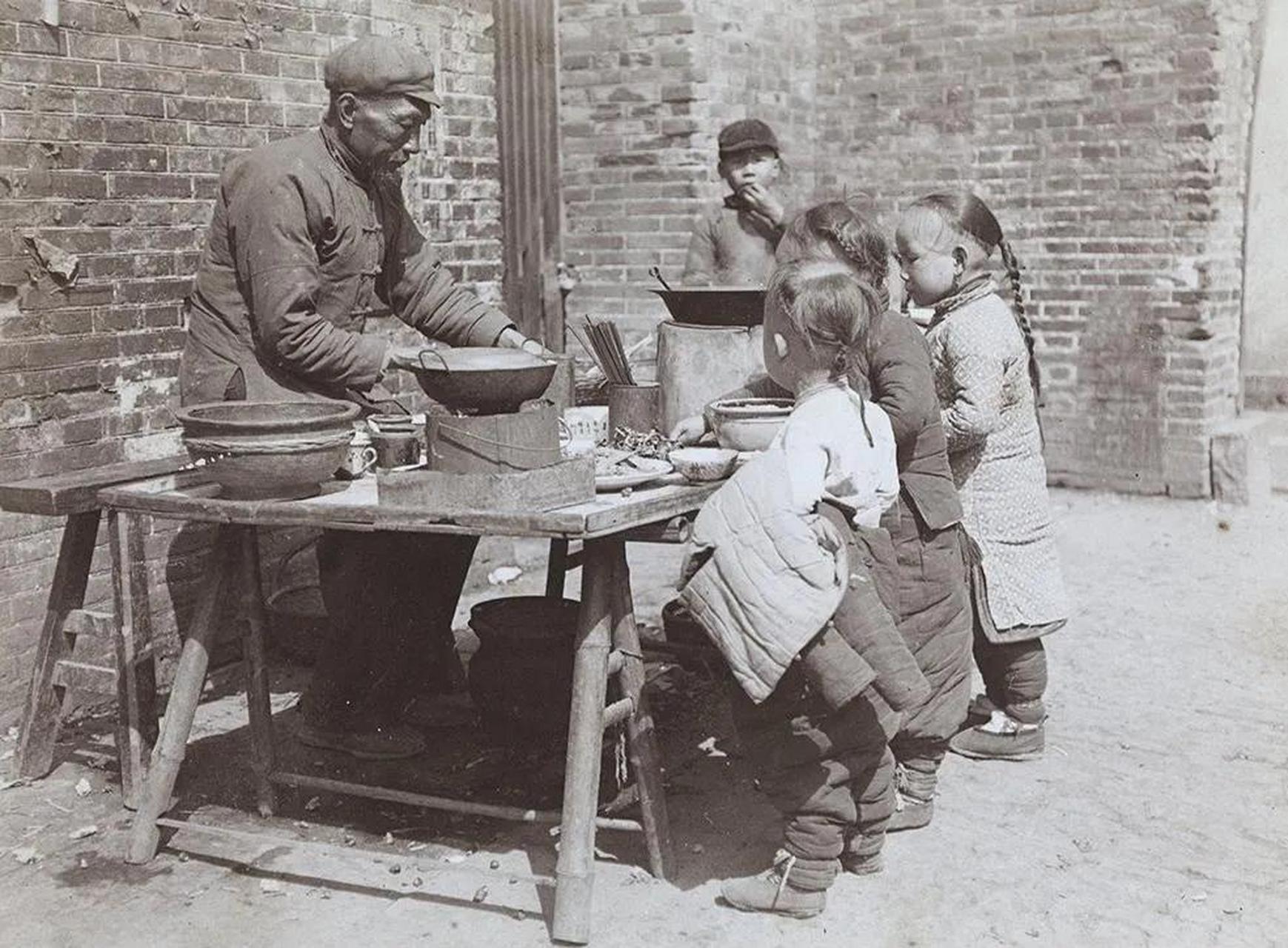 修补记忆碎片【老照片】清朝末年北京街头,孩子们在围着零食摊吃准备