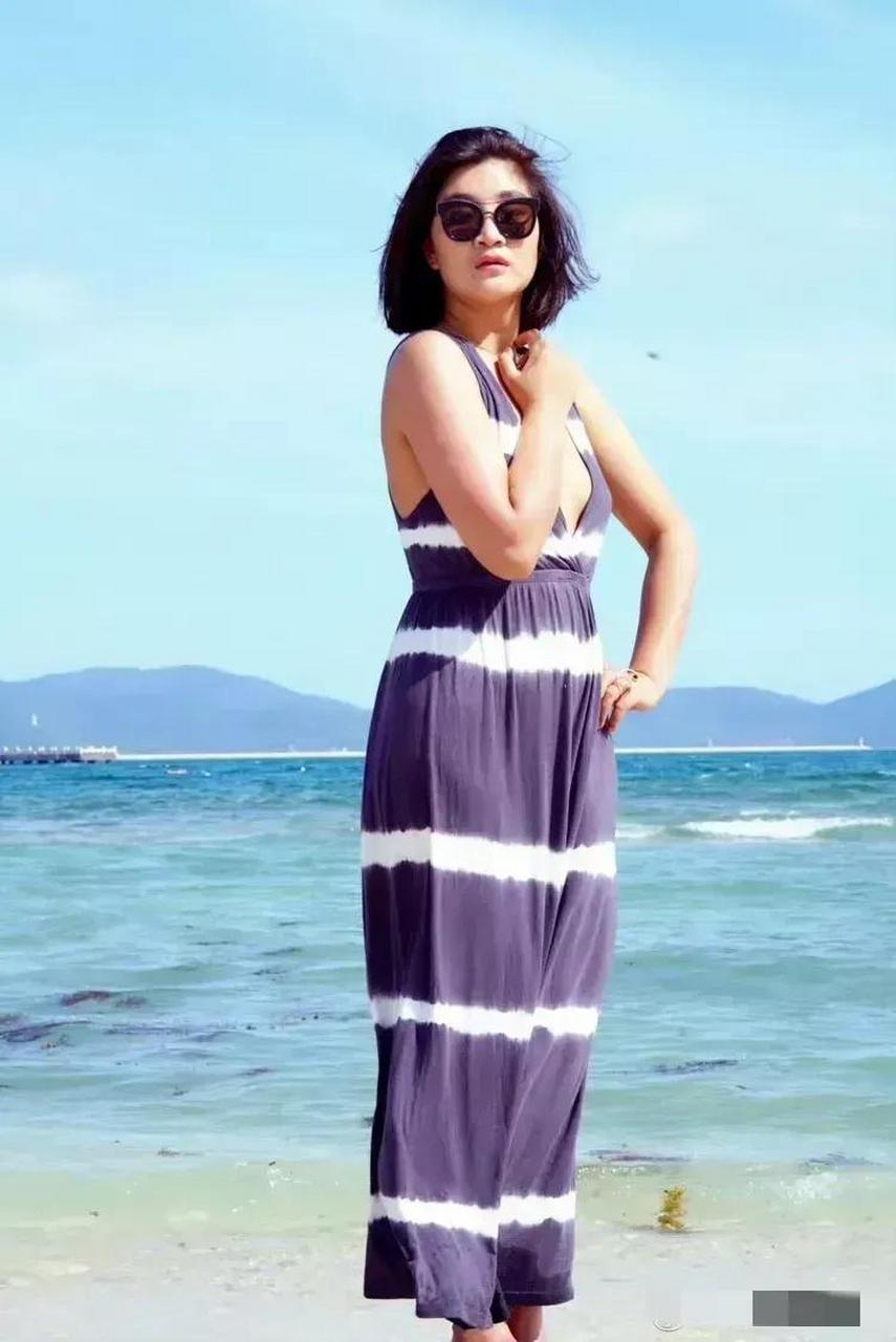 降央卓玛在海边素颜美照,穿紫色横纹吊带长裙出镜,随性洒脱,笑容