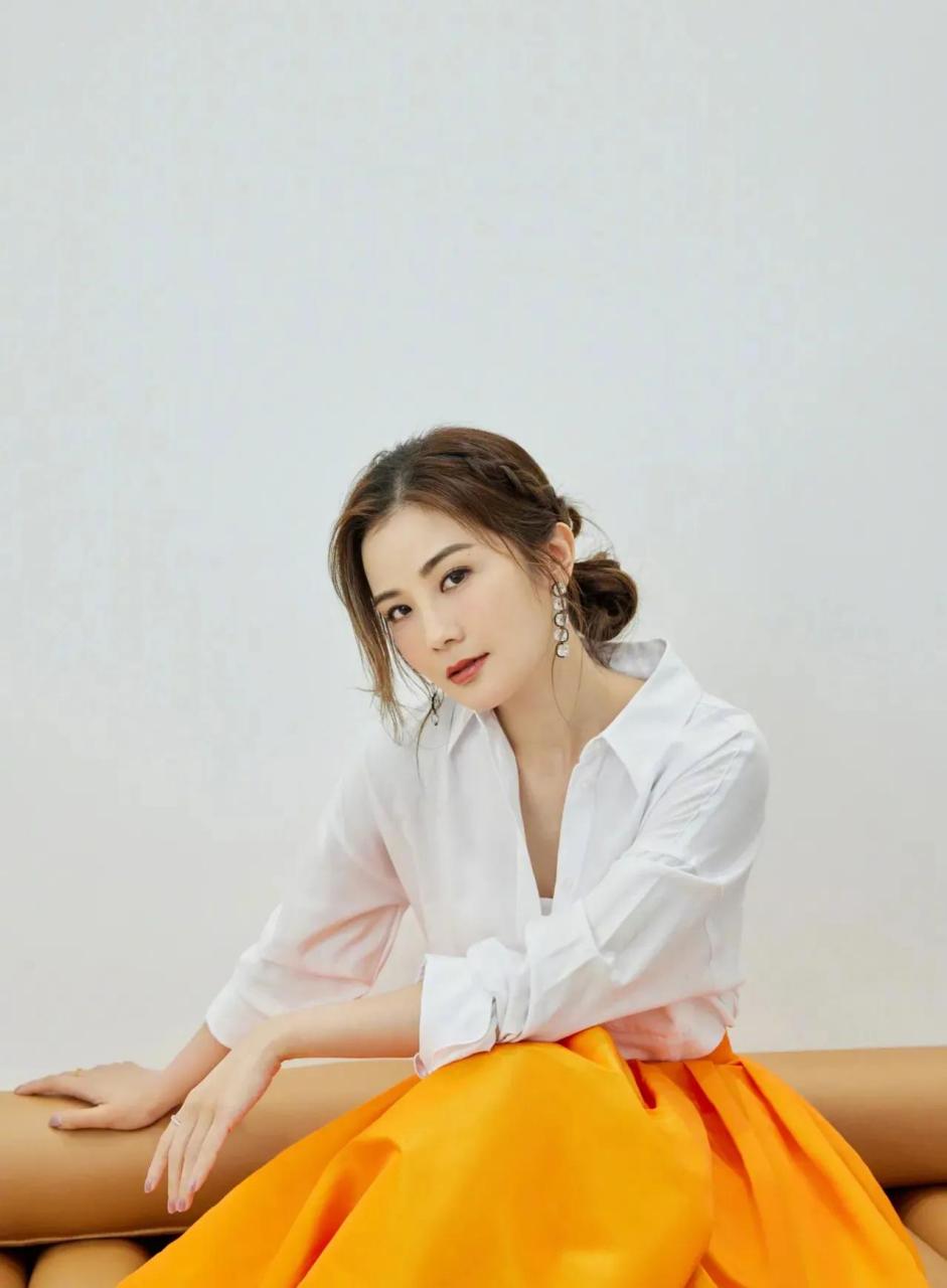 蔡卓妍一袭时尚白衬衫搭配橘色百褶长裙,气质高贵,青春靓丽,还是当年
