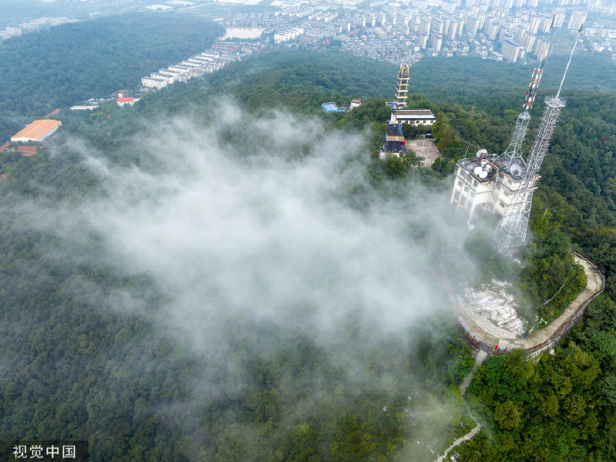 湖北省襄阳市,虎头山雨后云雾缭绕,雾气盘旋在山巅的电视塔建筑周边