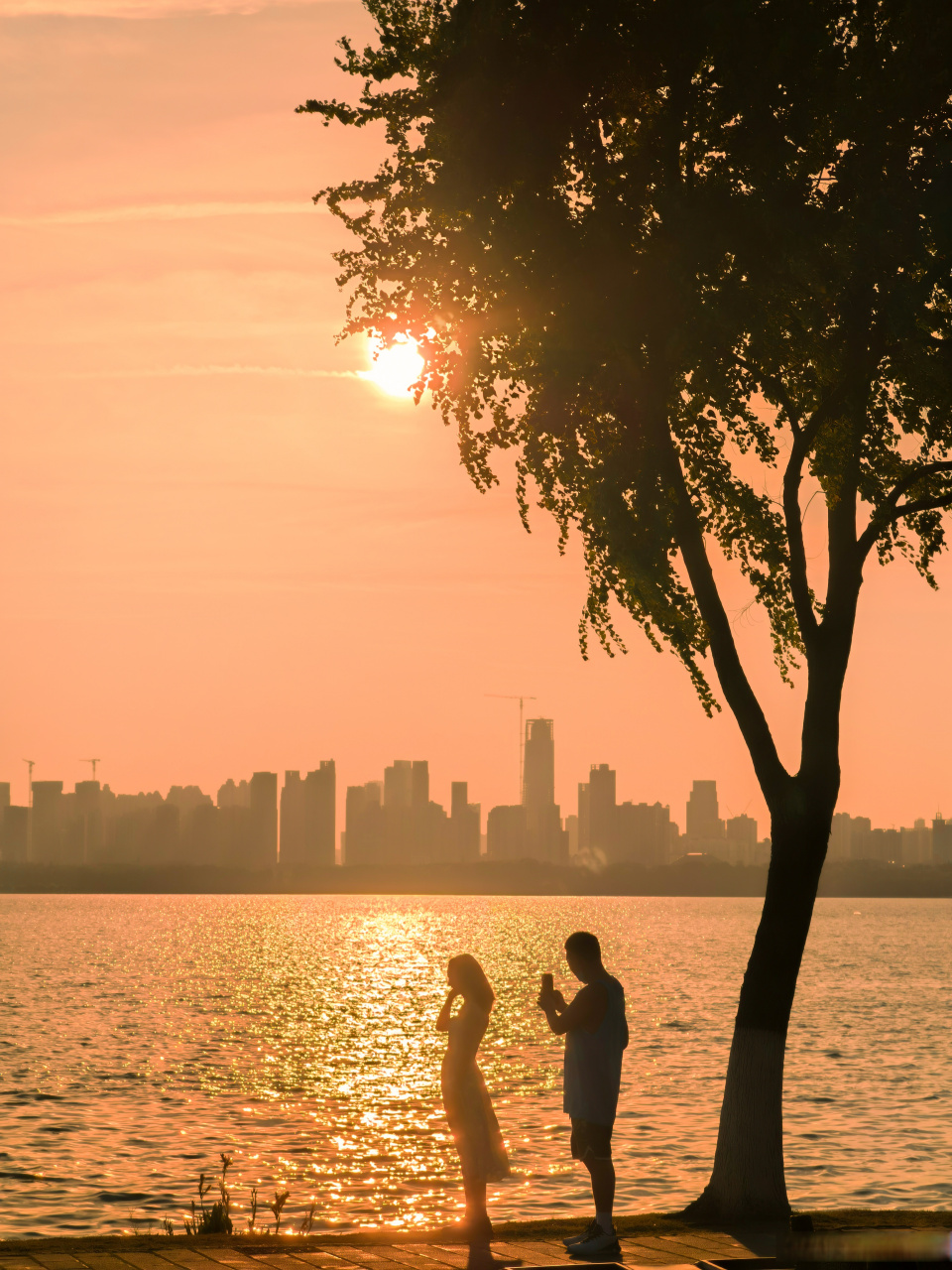 光影里的爱人  微风拂面,落日余晖,光影里的情侣在闪烁的湖光下变成了