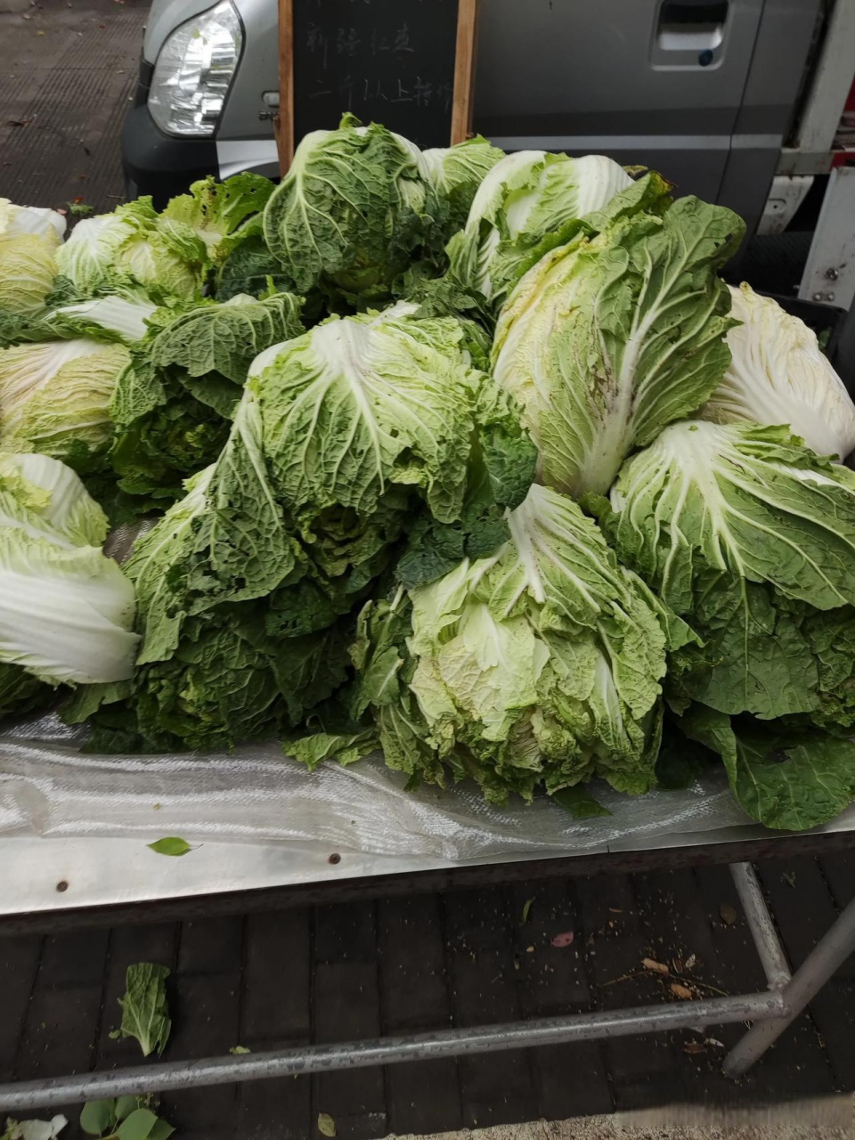 路边一农民摆摊卖大白菜,吆喝着十元三个.有人嘟嚷着还嫌贵.