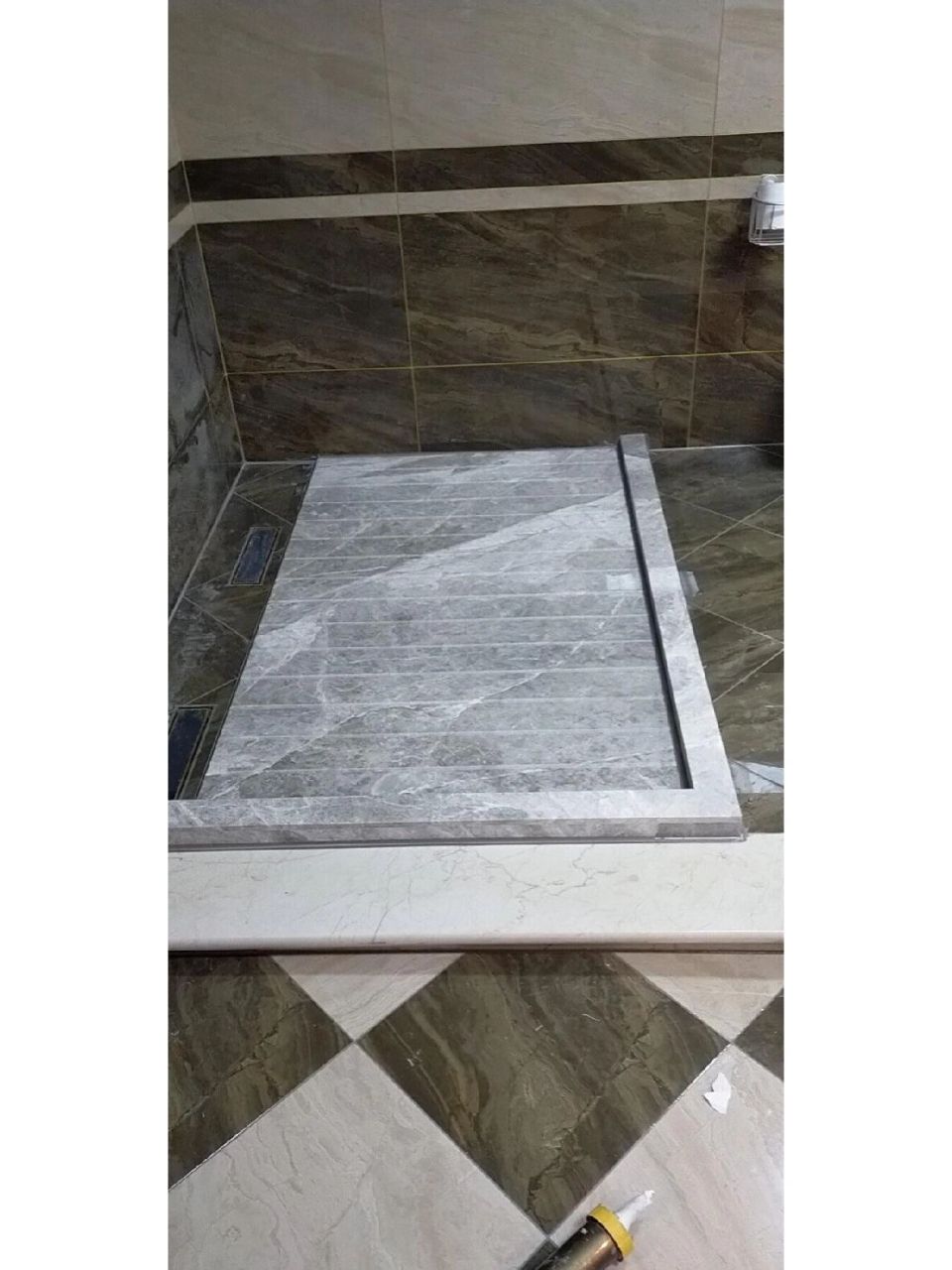 用机器进行拉槽加工,将其铺贴在淋浴房的中心,周围会有一圈导流排水槽