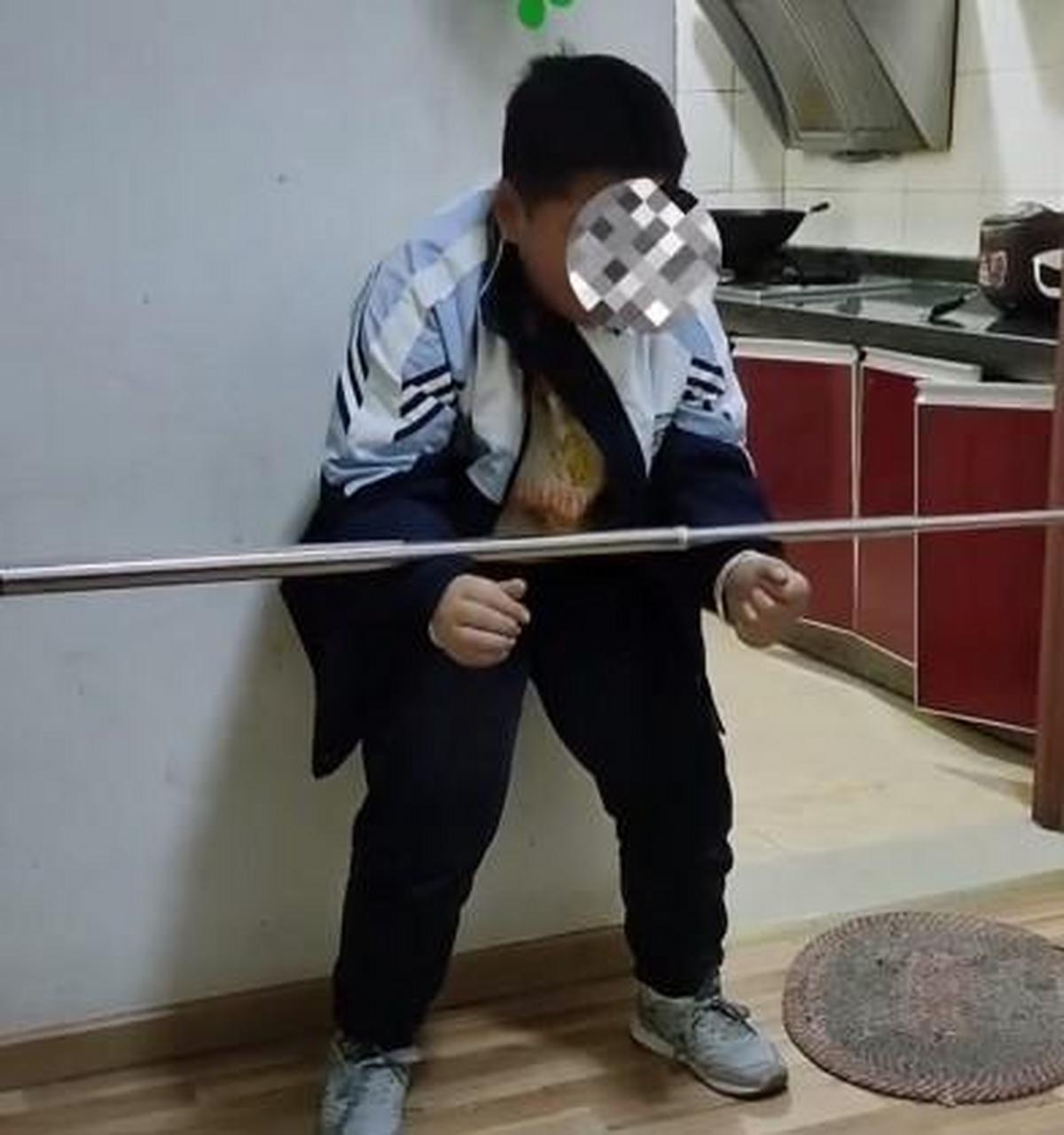 孩子没有完成作业,家长让其蹲马步,手上还放了一个不锈钢杆子