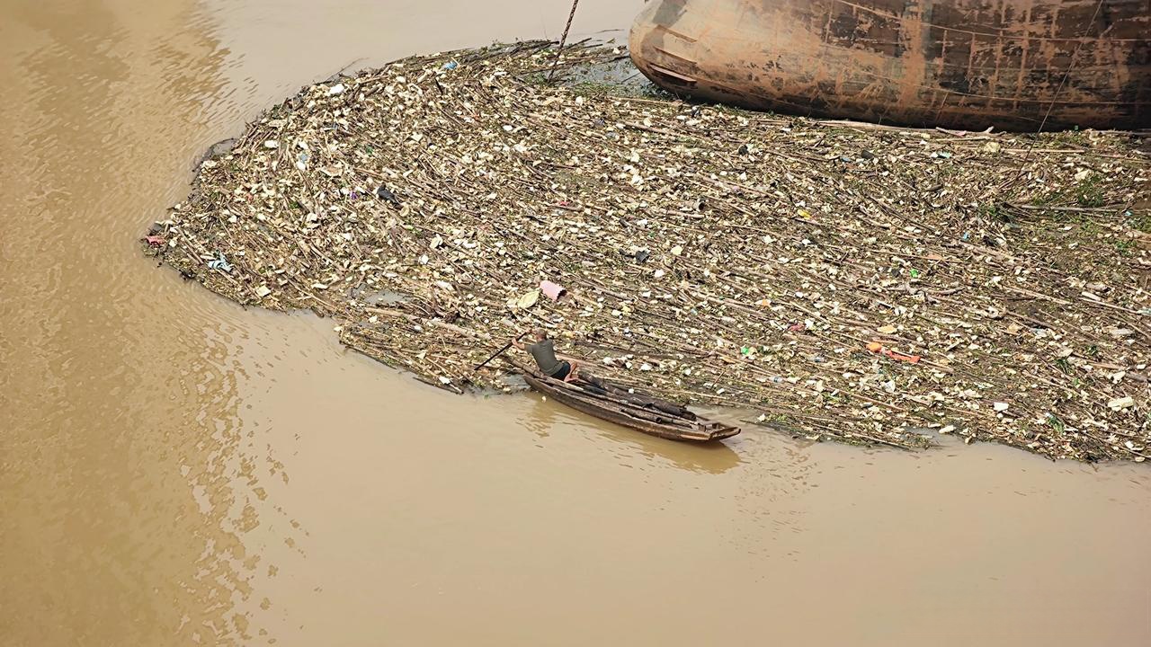 看他的小船上放了一些竹竿,难道他是捡水上这堆垃圾里的竹