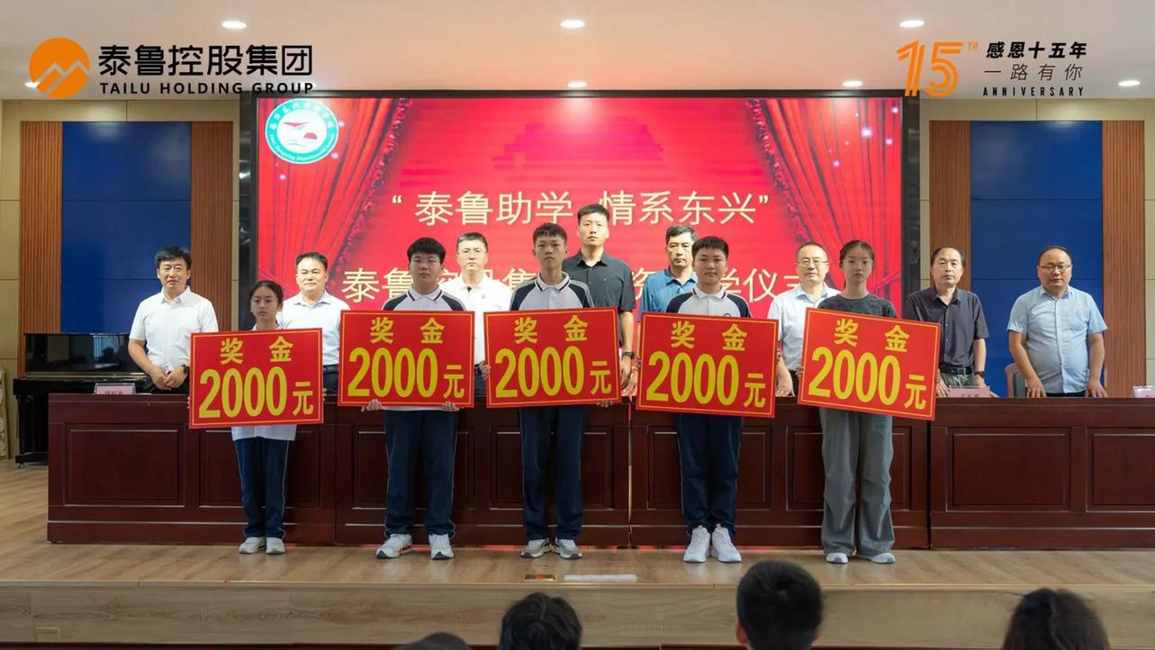 台上优秀学子们手握奖金牌,河东区东兴实验学校和泰鲁集团为他们颁奖