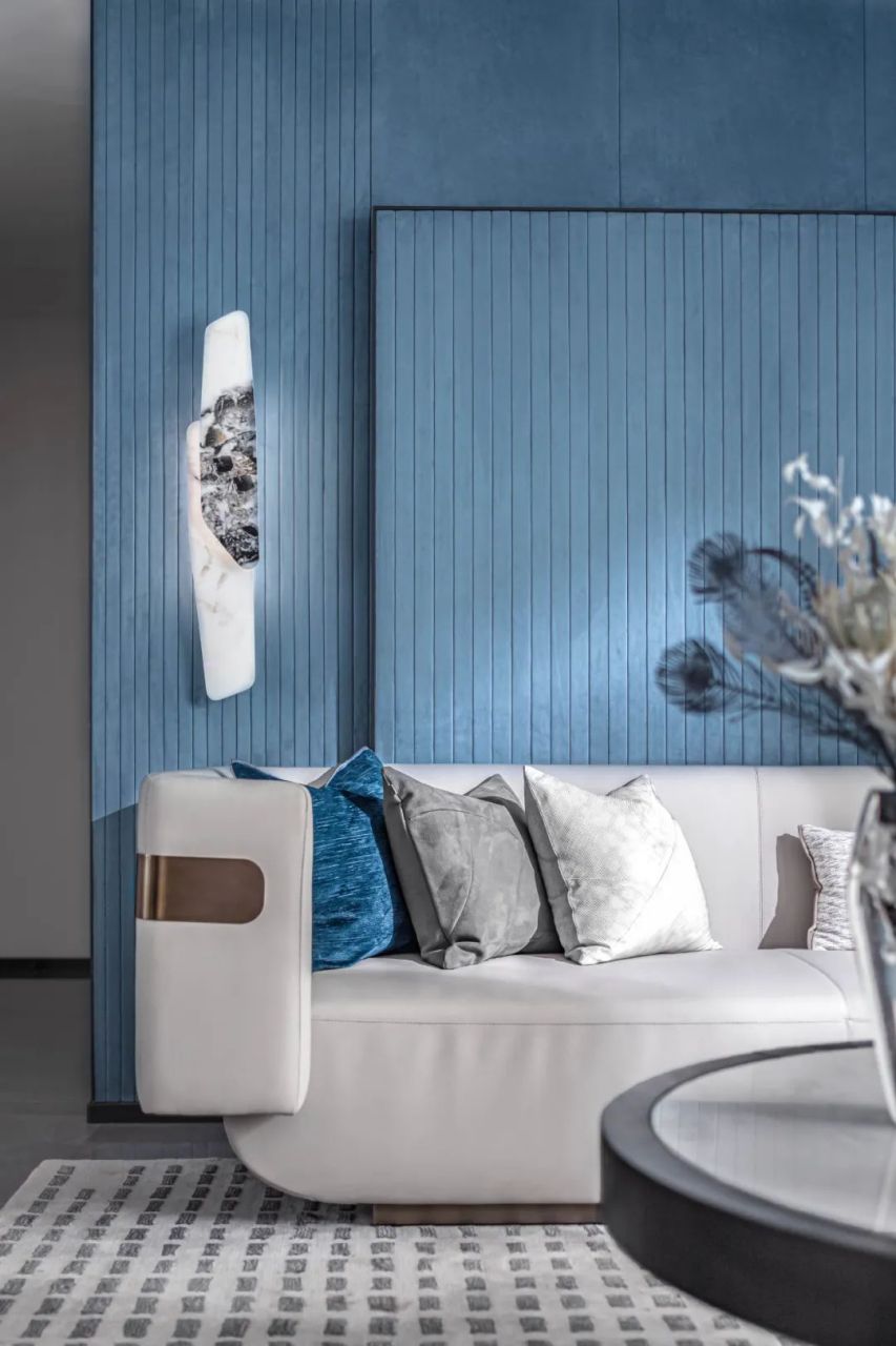 丝绒质感的湖蓝色背景墙,美化了整个空间的轻奢感,雅白色沙发与金属边