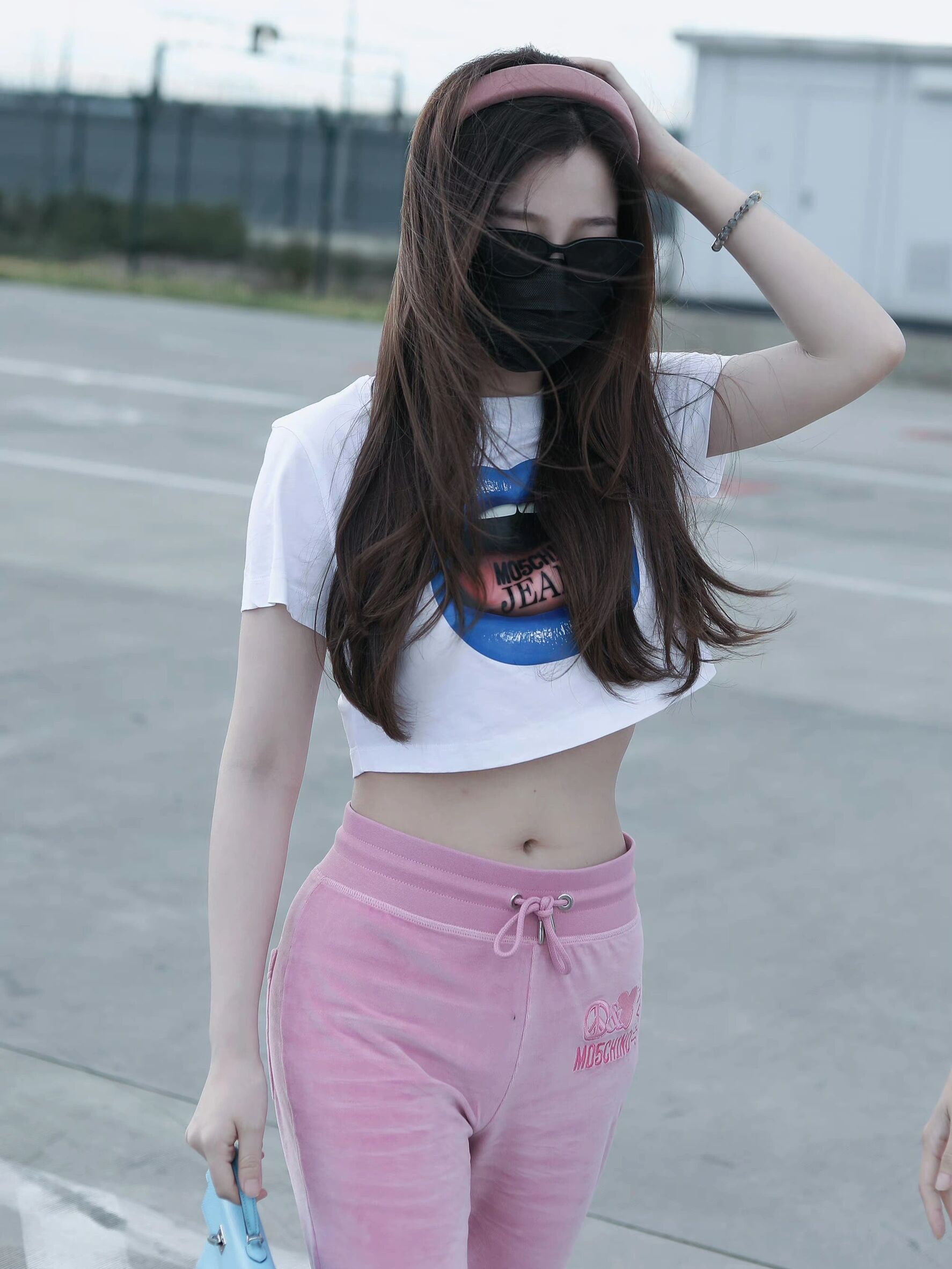 虞书欣230708机场穿搭,印花crop top搭配粉色长裤与运动鞋,手拎蓝色