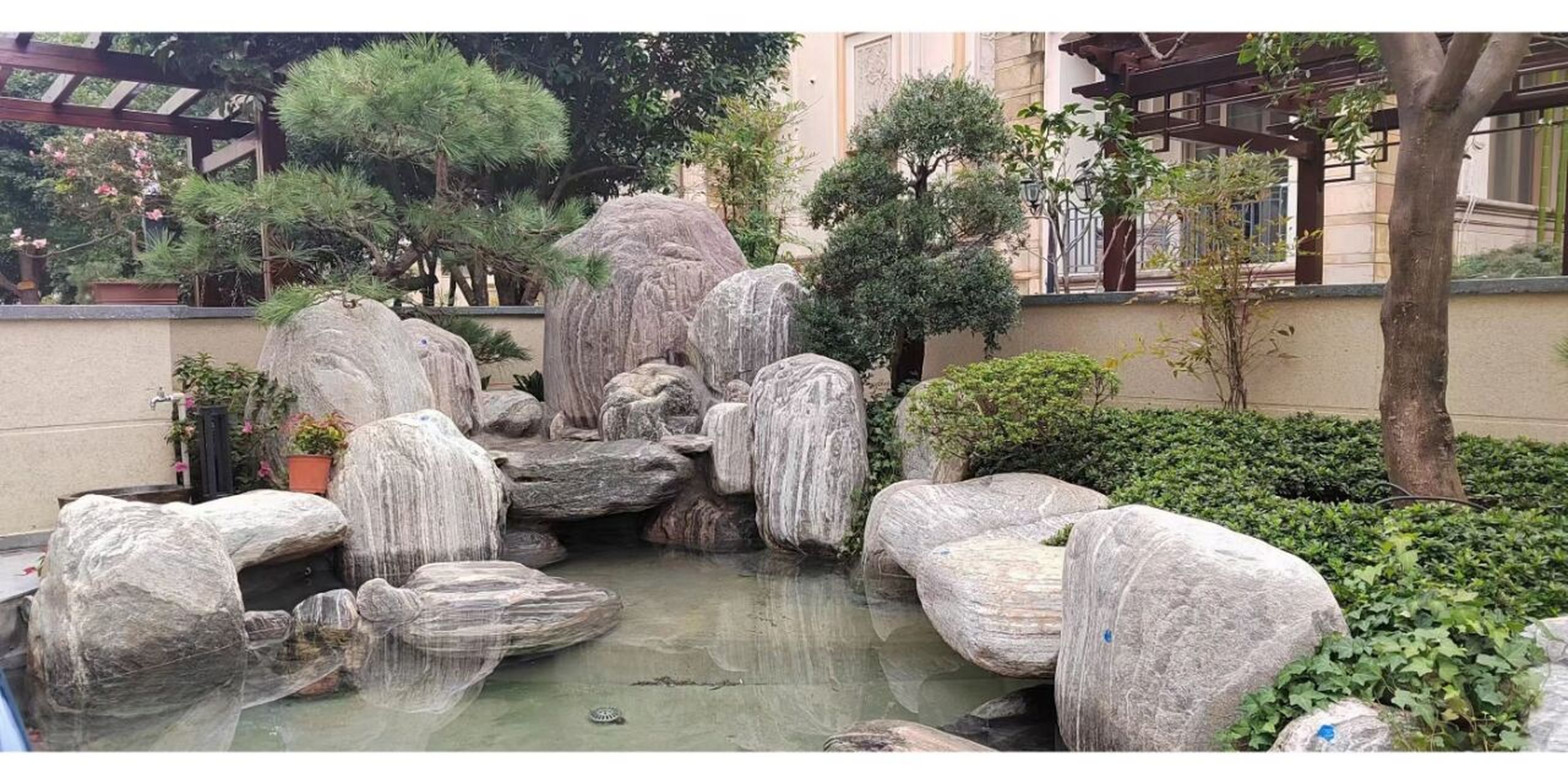 很多人喜欢用黑山石或是黄蜡石作为鱼池假山驳岸,但其实泰山石做鱼池