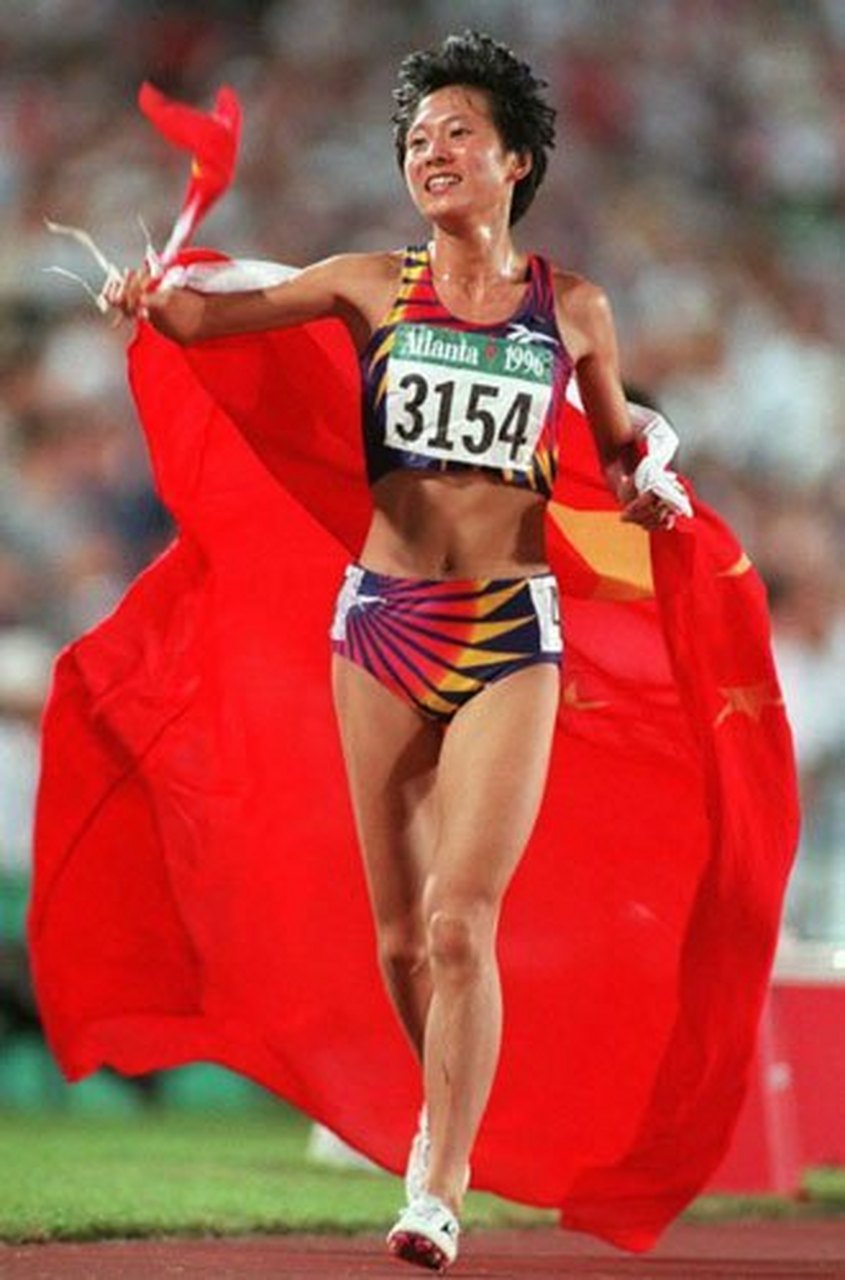 身披国旗跑步,中国运动员王军霞冲过终点之后,她接过留学生扔到她手上