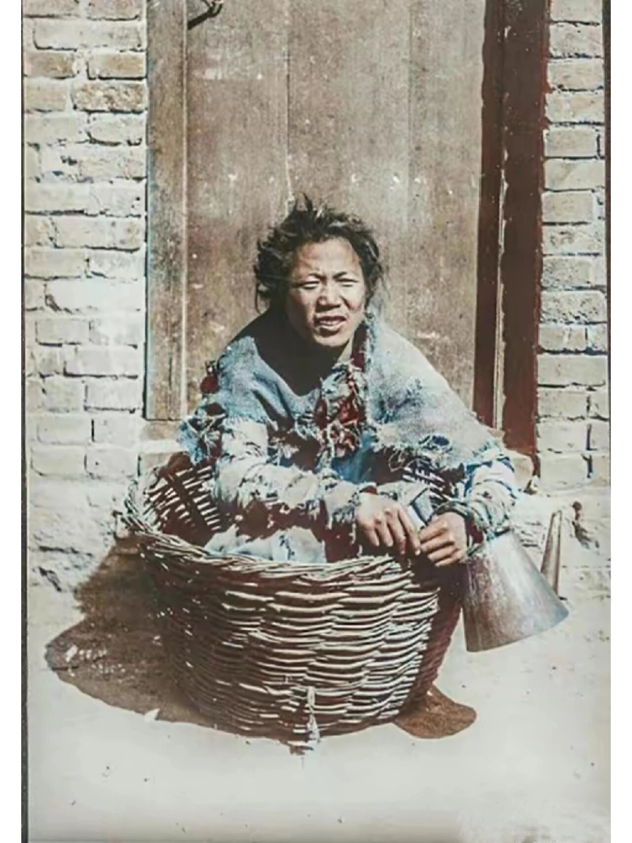清末老照片,坐在筐子里的乞丐 这个乞丐的衣服早已残破不堪,肩上还