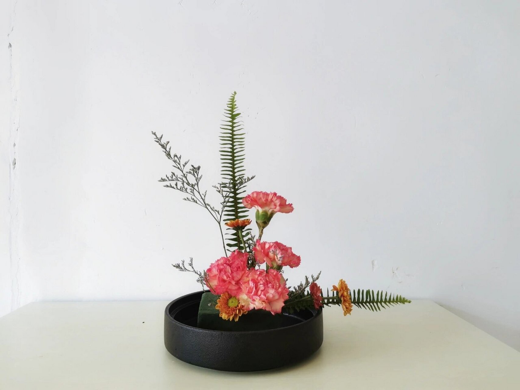 西方l型插花 命名:拥抱 花材:桃红康乃馨,雏菊,情人草,排草 立意:本次