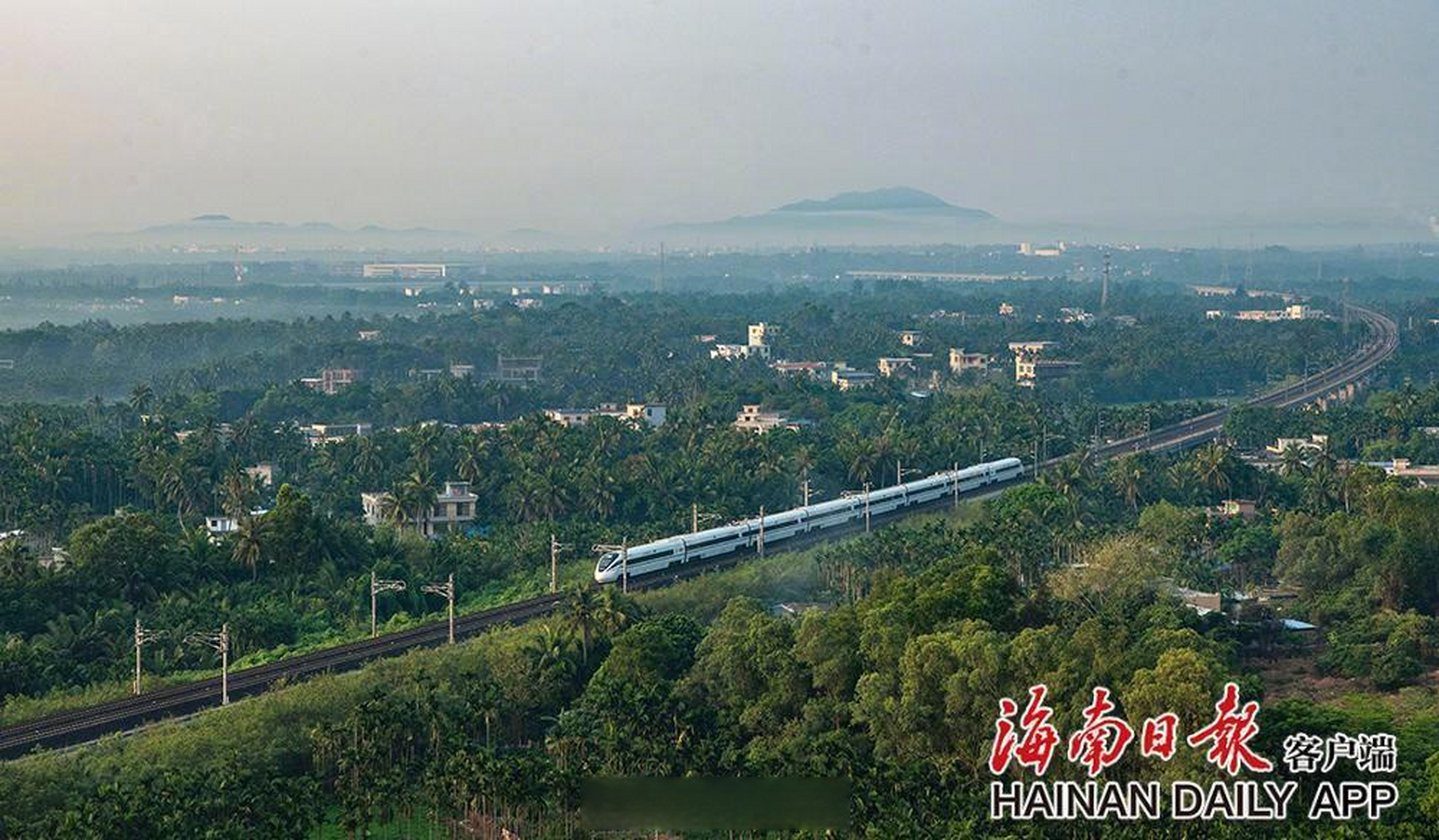 春暖花開時節,海南環島鐵路一列列動車在春光明媚的椰林村莊和曠野中