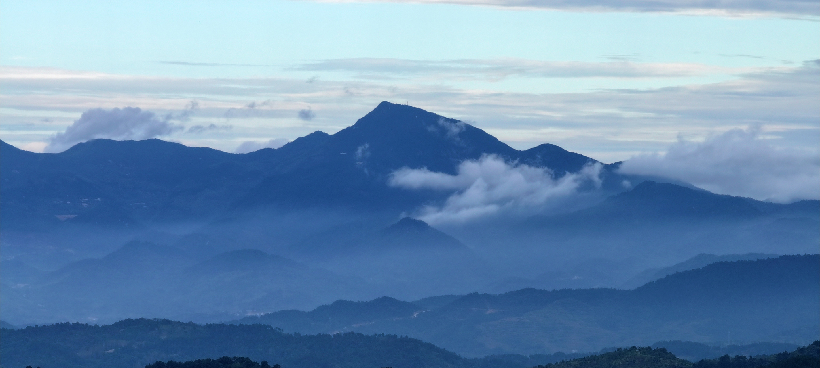 在长焦镜头下,大别山脉的风景秀丽,整体泛着深蓝,云在半山腰,如丝如