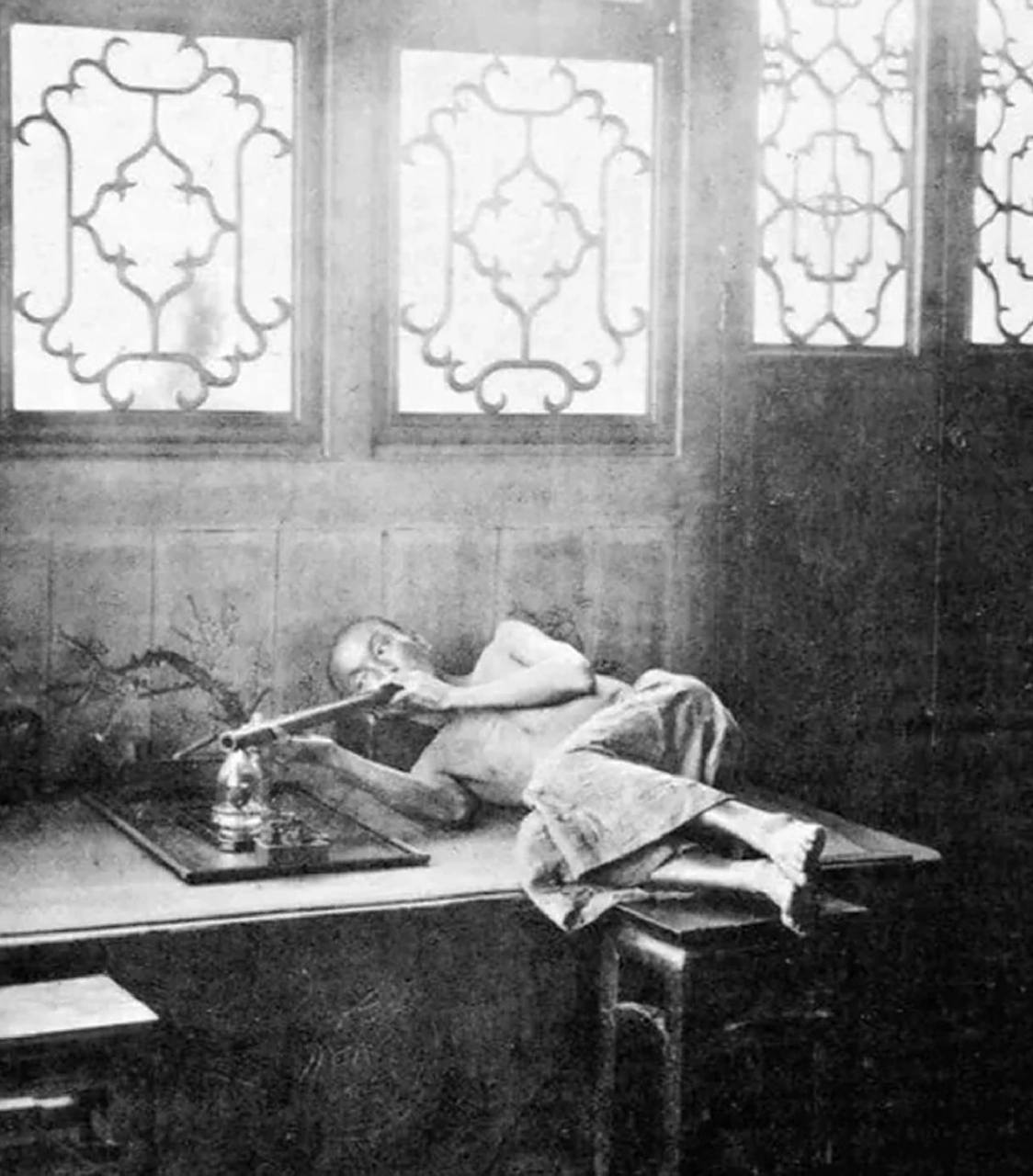 男人正在躺着抽大烟,瘦骨嶙峋,深受鸦片毒害.