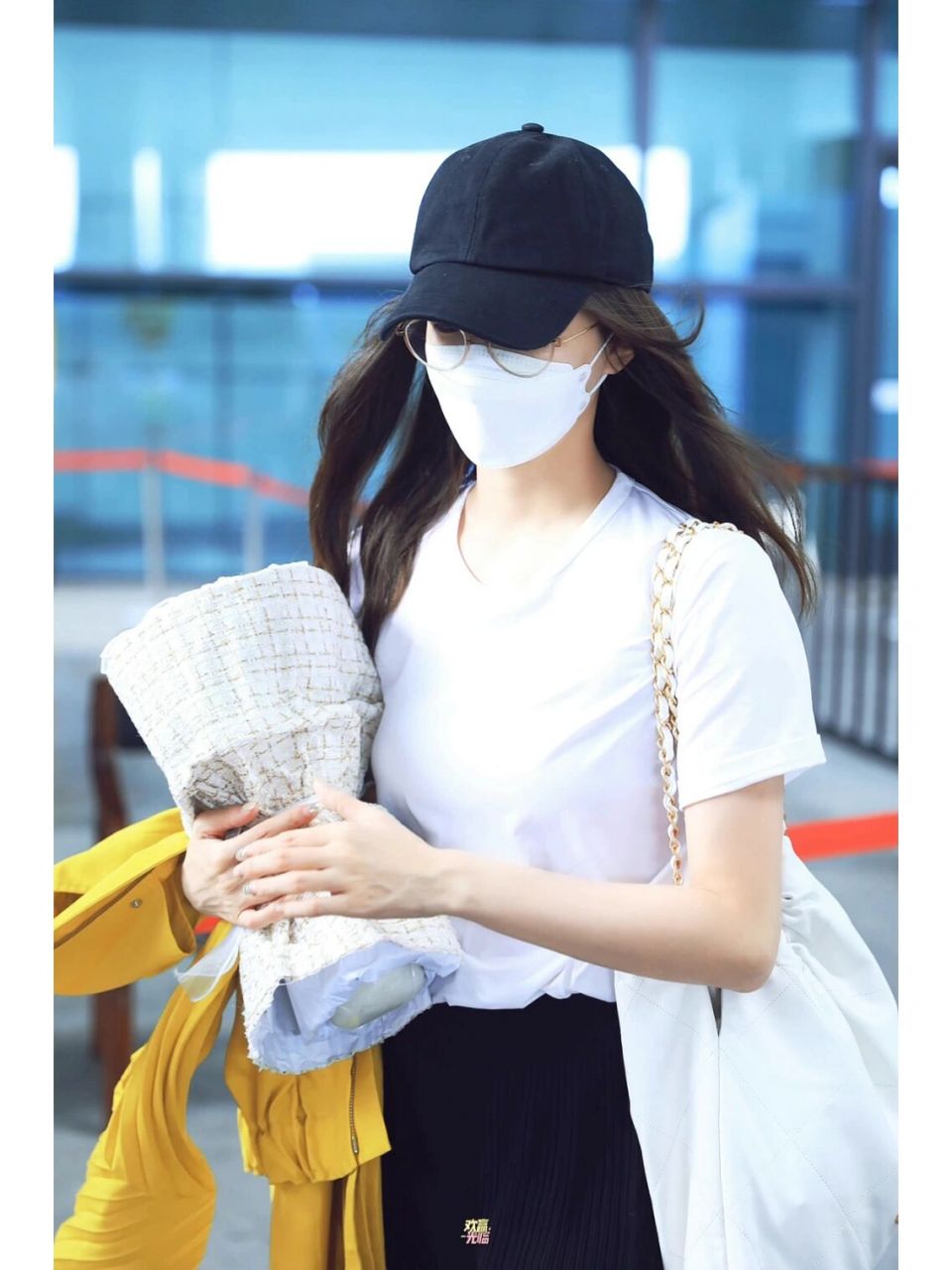 江疏影220901机场私服,白色t恤搭配黑色褶皱半身裙与棒球帽,外搭芥末