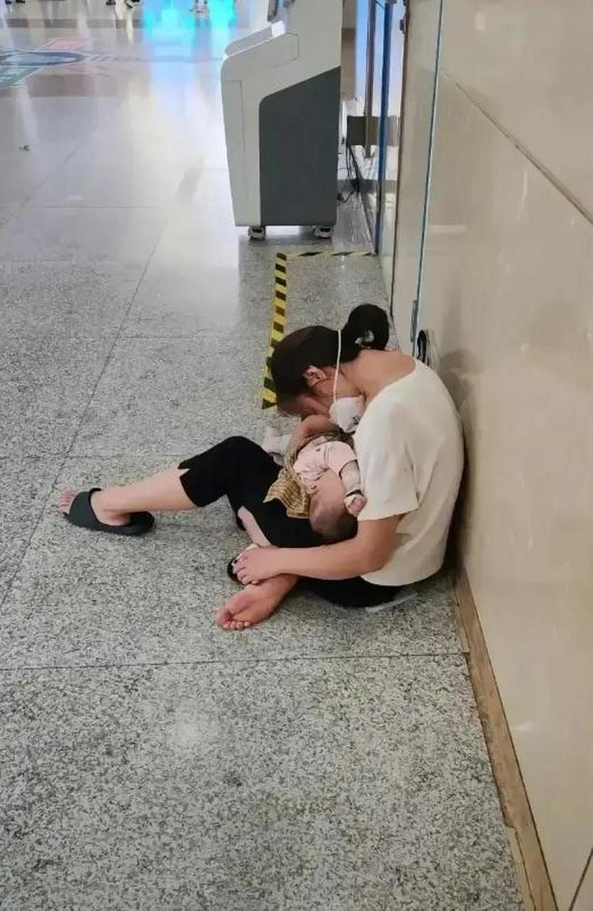 在医院的漫长走廊上,一位母亲的身影靠在冰冷的墙边,她的双手紧紧地抱