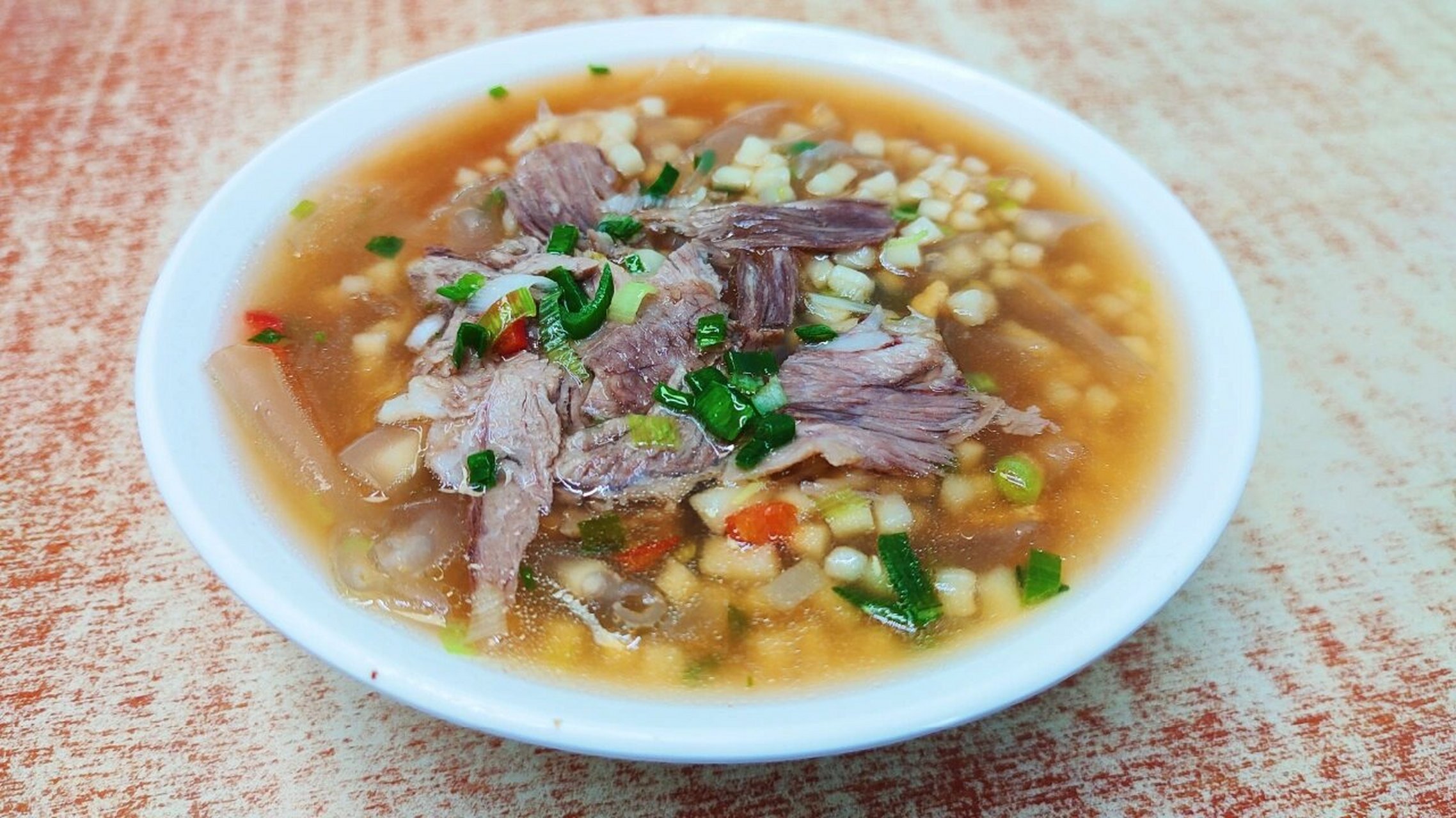 一锅牛肉汤中将面,粉,豆腐等食材制熟,盛在碗里,盖上一层牛肉.