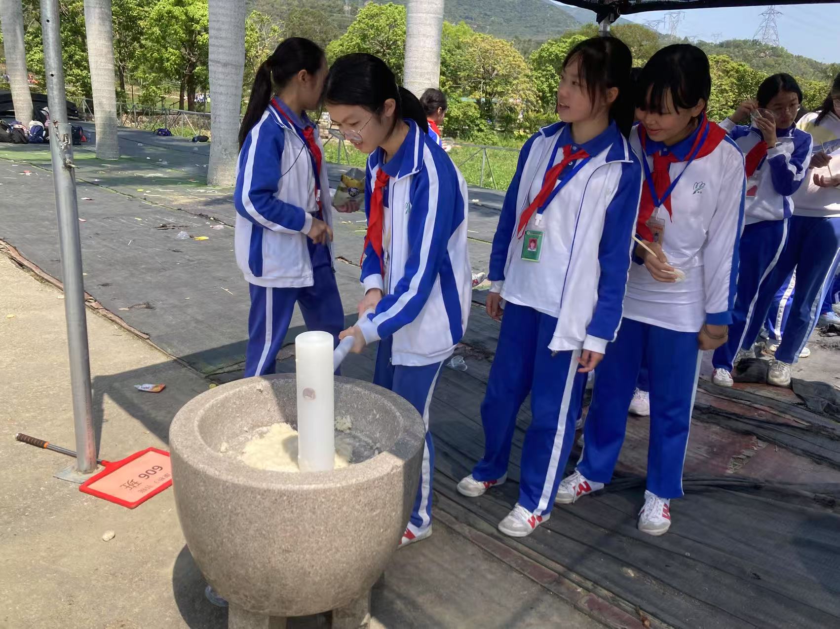 2025康桥春游,这群蓝白校服的女孩们围着一个石碾子