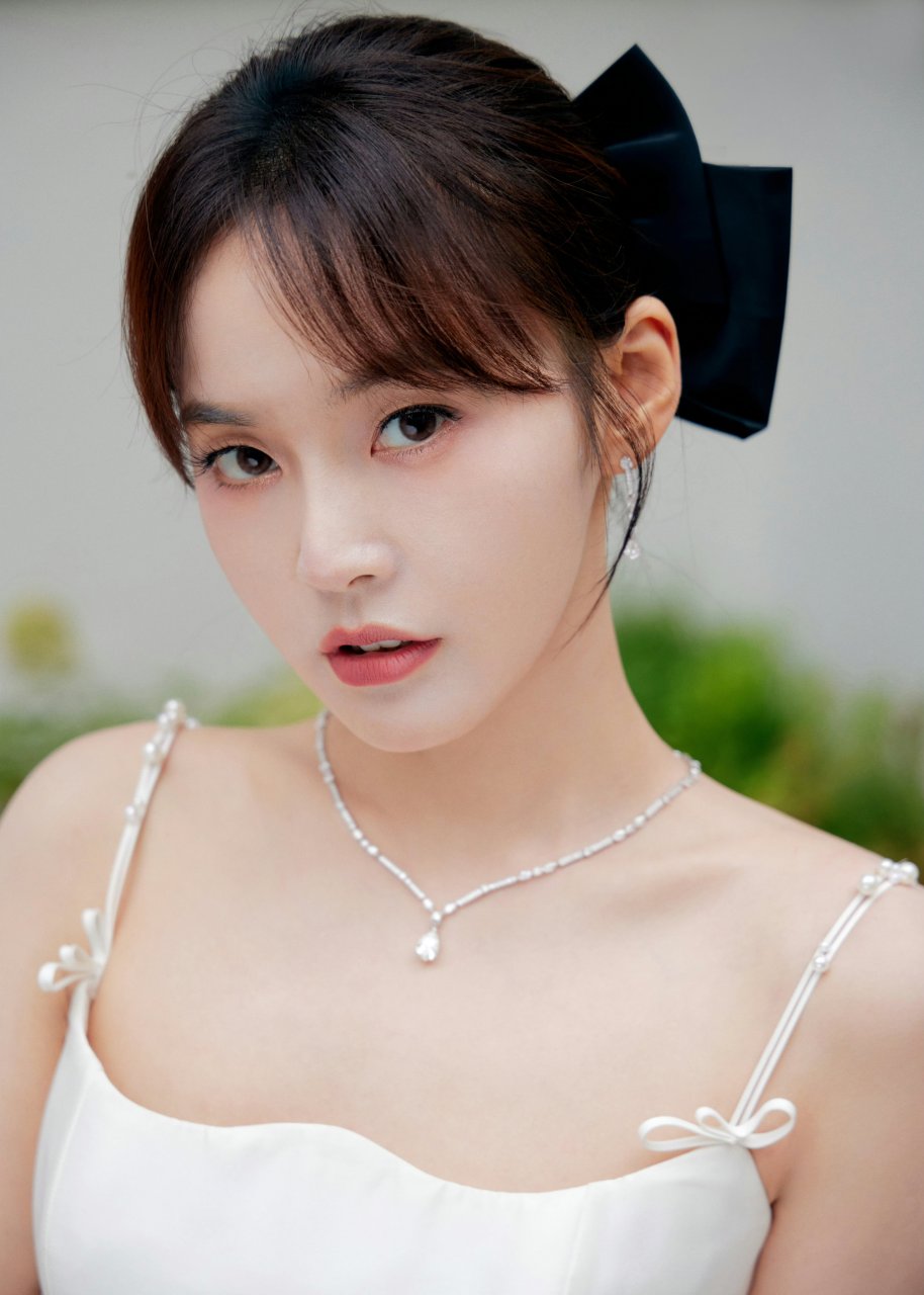 粉花丛中,张佳宁身穿白色连衣裙,头戴黑色蝴蝶结,优雅又甜美.