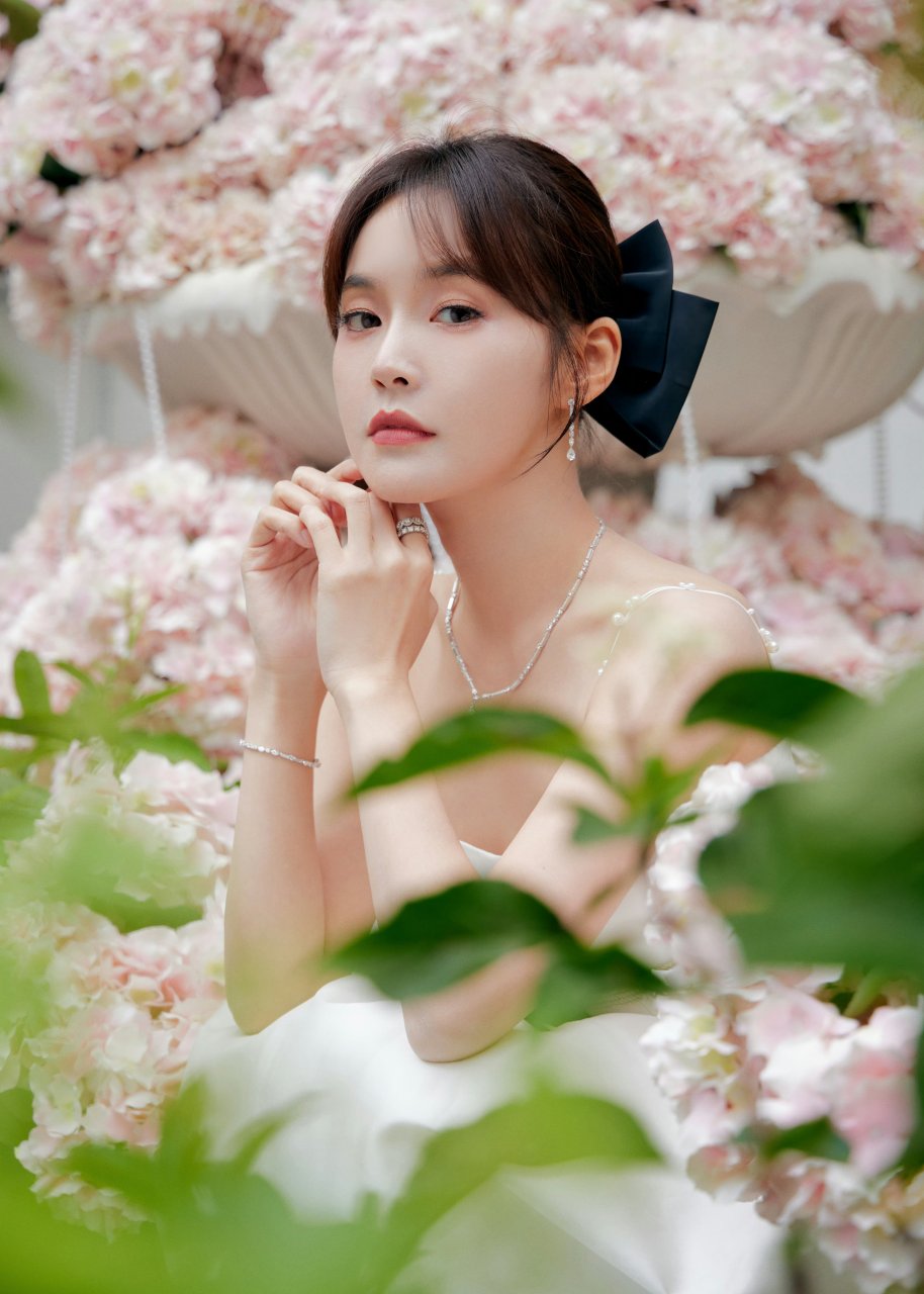 粉花丛中,张佳宁身穿白色连衣裙,头戴黑色蝴蝶结,优雅又甜美.