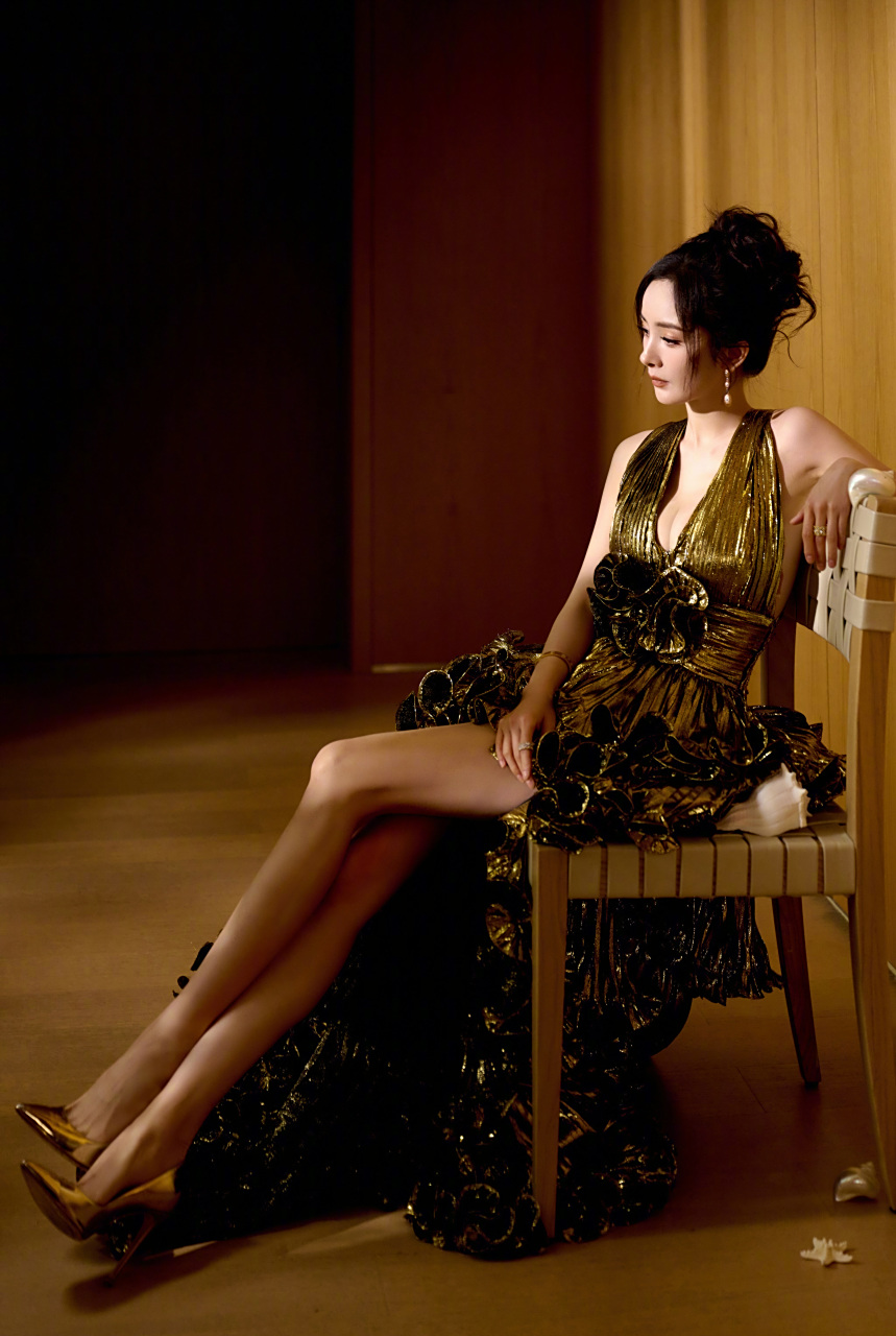 在光影交错中,杨幂身穿金色低胸长裙,优雅侧身,眼神流露出无限的故事.
