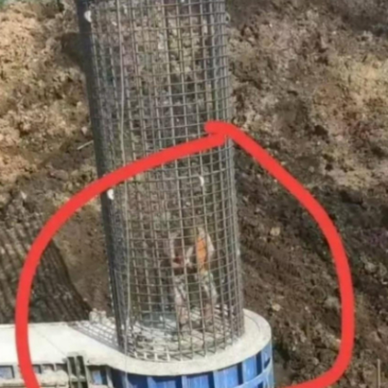 在建筑工地上,一名工人正站在钢筋笼内,红色的圆圈突出了他的位置.