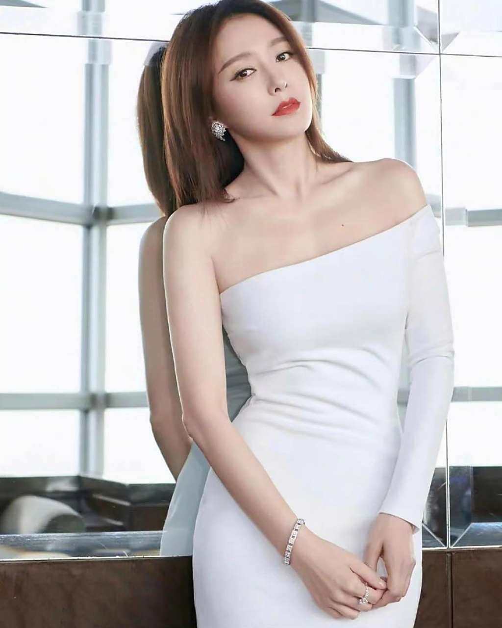 秦岚是一个非常漂亮的女性,她身穿白色抹胸裹身连衣裙,展现了她优美的