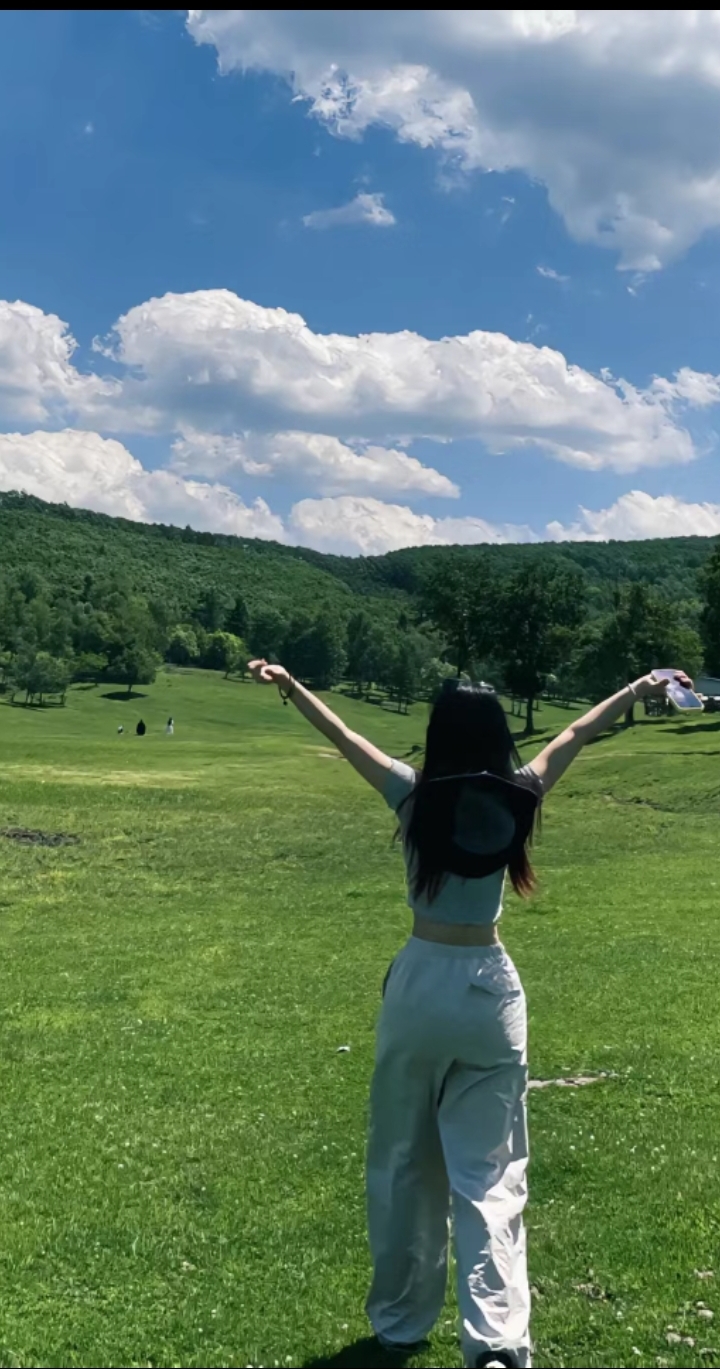 绿茵茵的草地上,女孩张开双臂,拥抱这美好的一天.