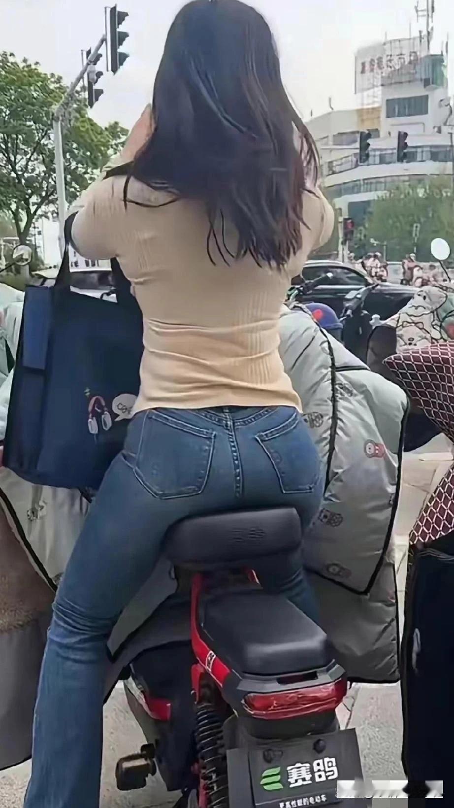 前面红绿灯路口堵车了,这位美女骑着电动车一点也不着急,拿出手机拍个