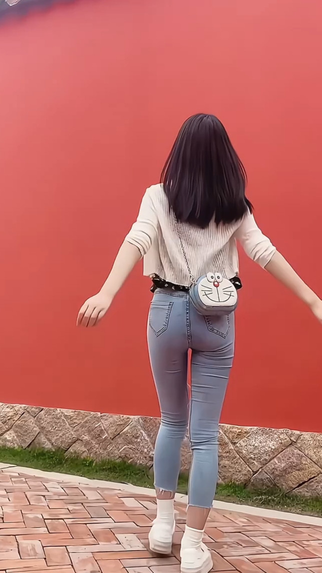 她走在一堵红墙旁边,手舞足蹈的玩自拍,说实在的,她的身材好看极了.