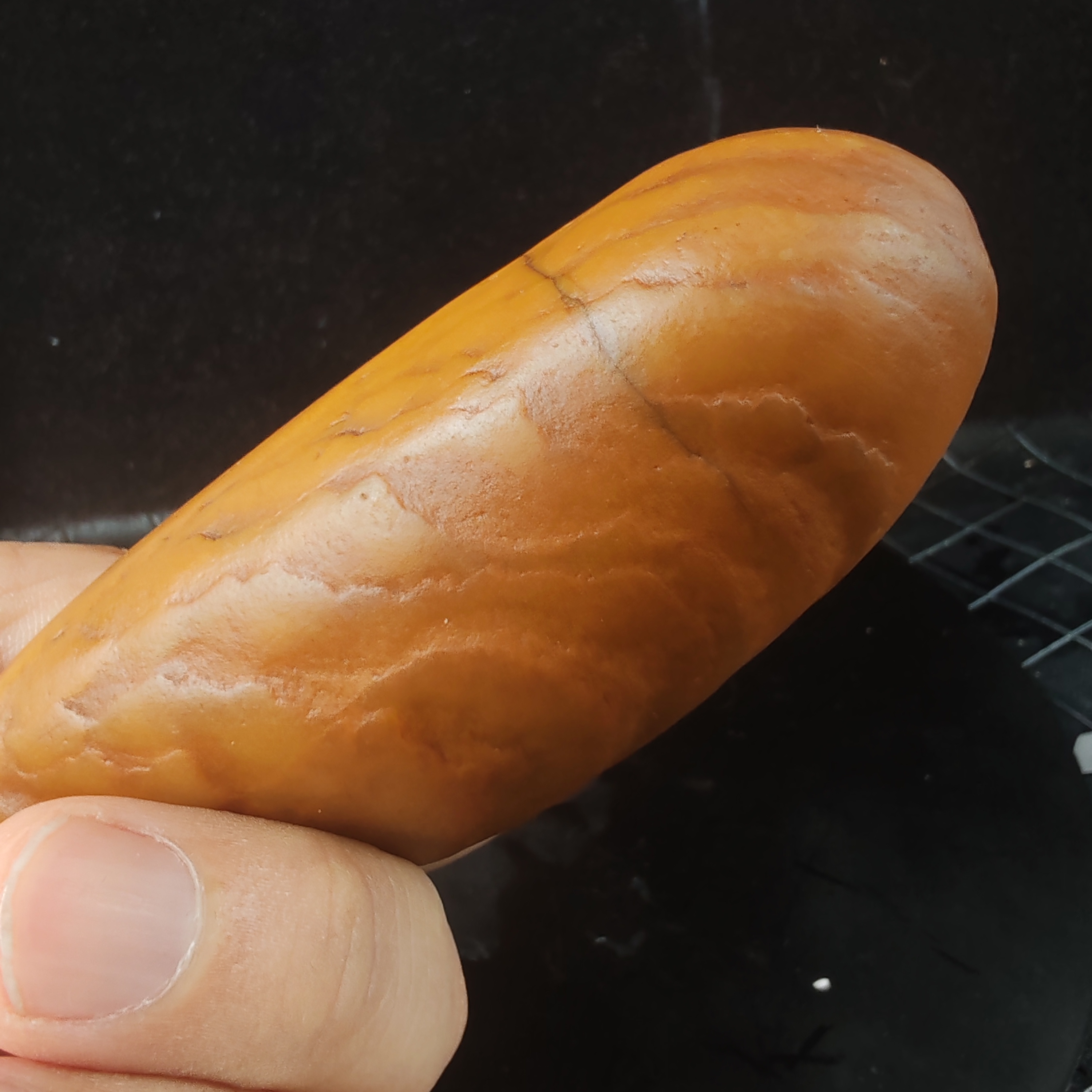 在手中,一块黄龙玉原石籽料手把件散发着独特魅力.