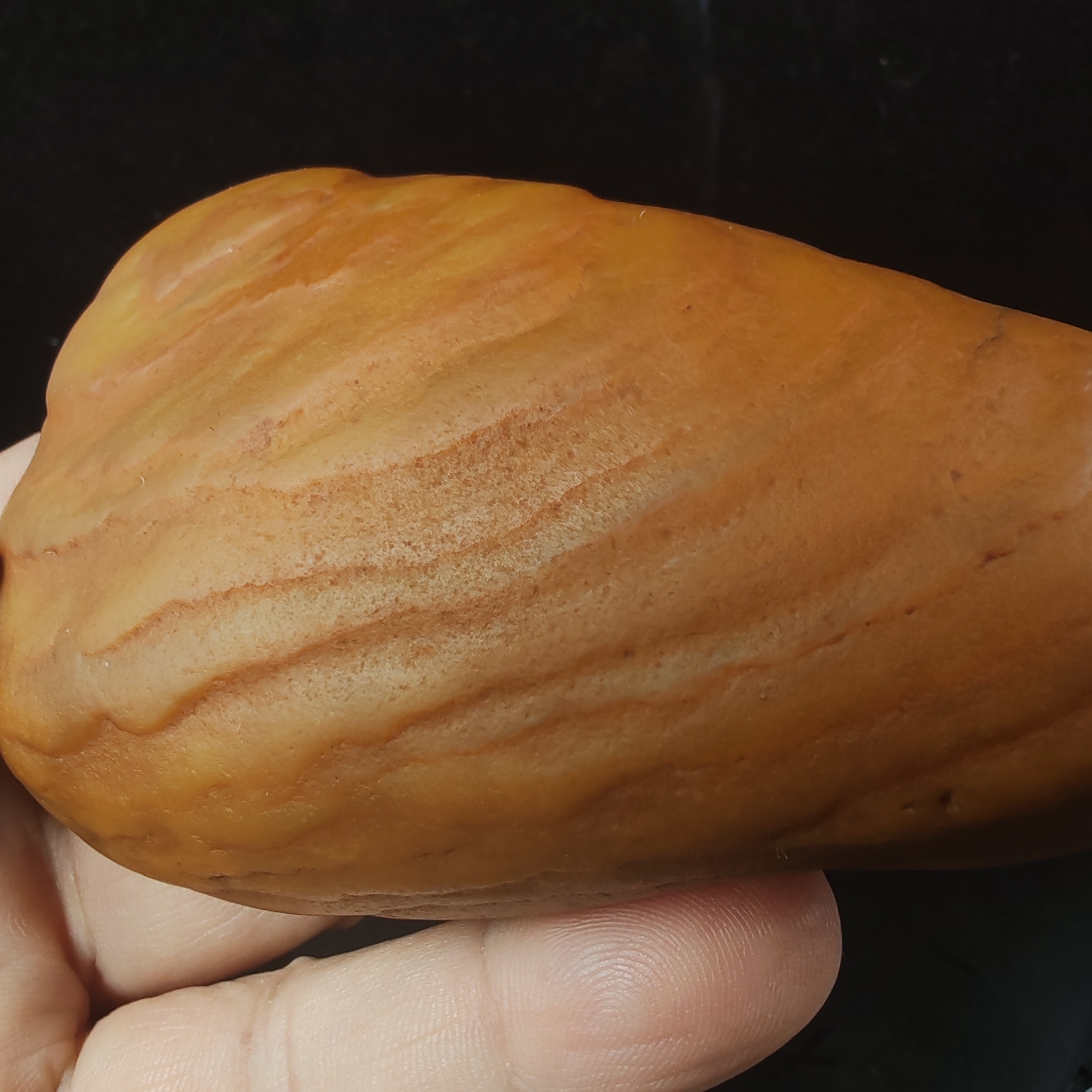 在手中,一块黄龙玉原石籽料手把件散发着独特魅力.