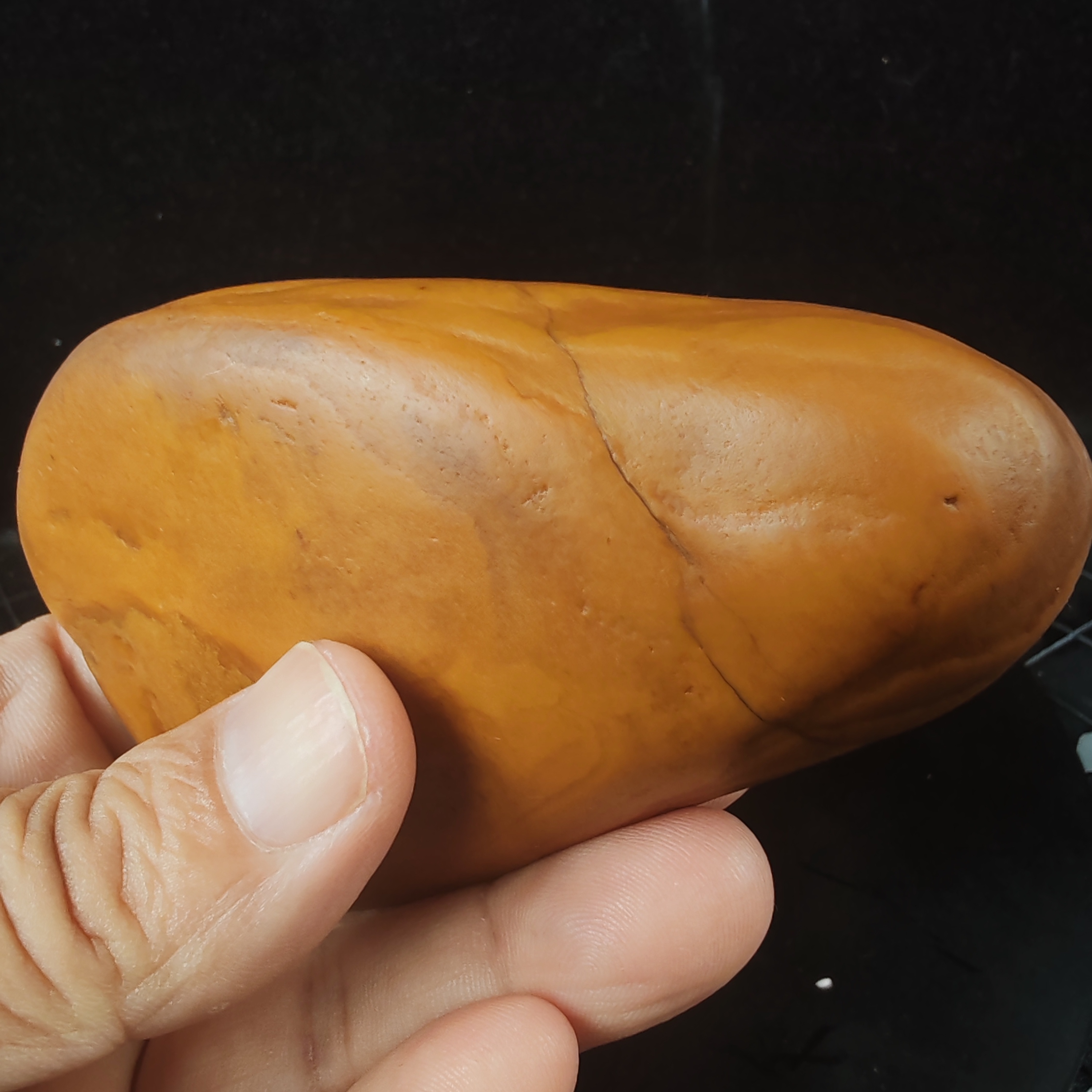 在手中,一块黄龙玉原石籽料手把件散发着独特魅力.