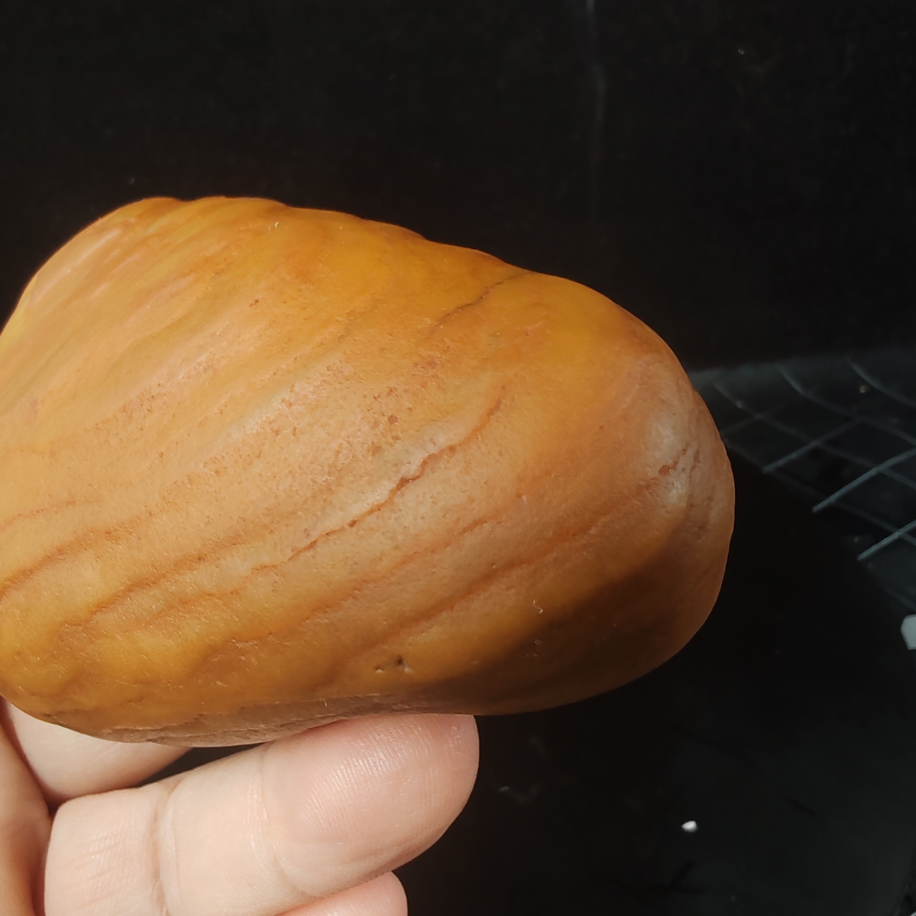 在手中,一块黄龙玉原石籽料手把件散发着独特魅力