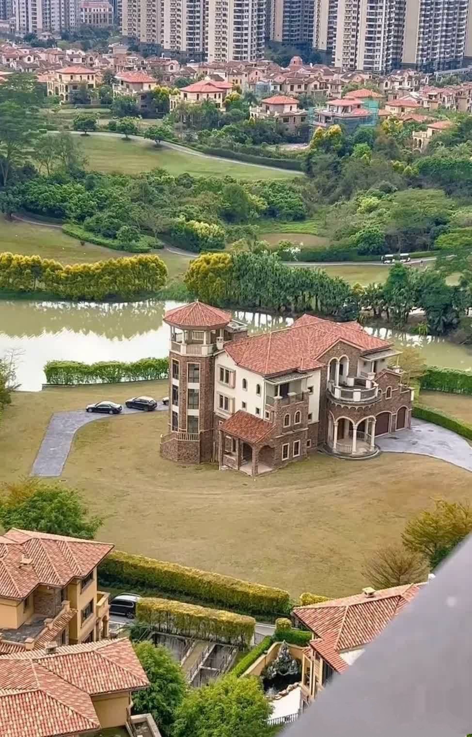 在这片宁静的湖畔,一套套红瓦屋顶的别墅房子错落有致,湖水如镜,映照