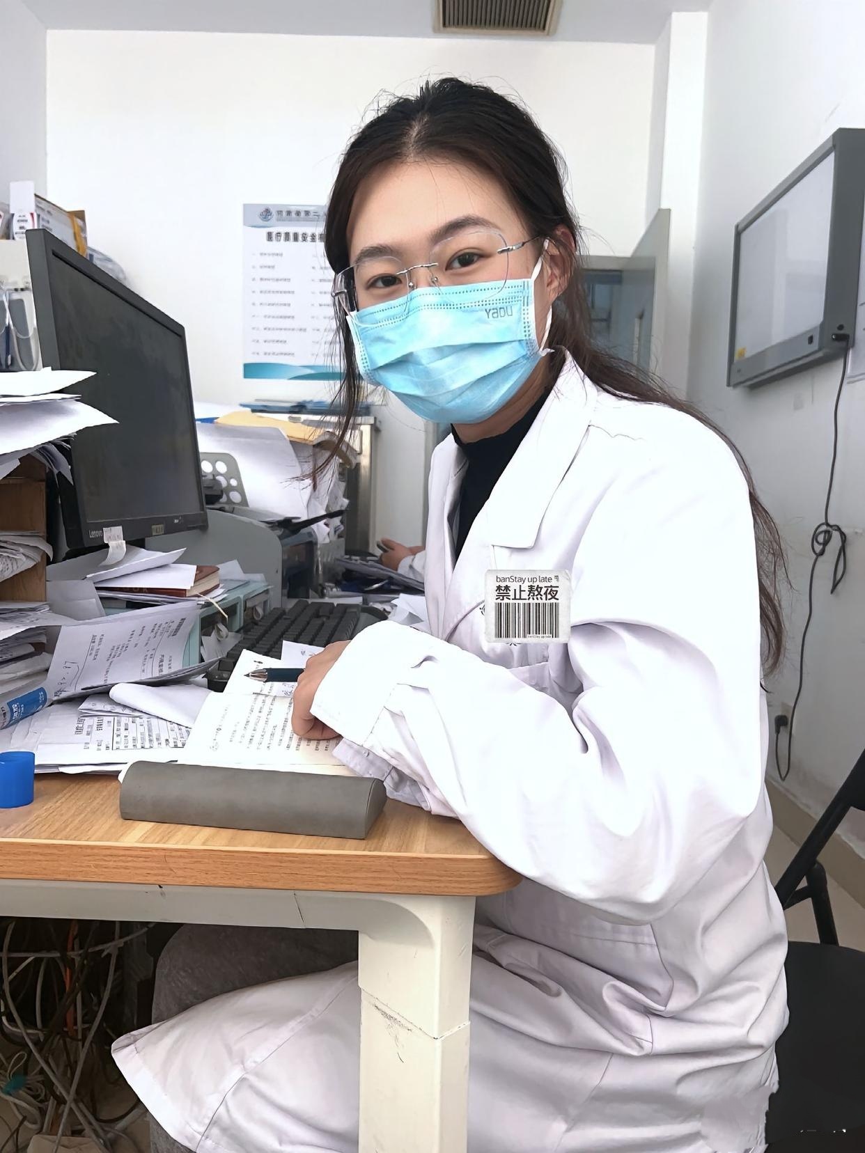 女医生身着白大褂,专注地敲击键盘,蓝色口罩掩映下的坚毅眼神透露出
